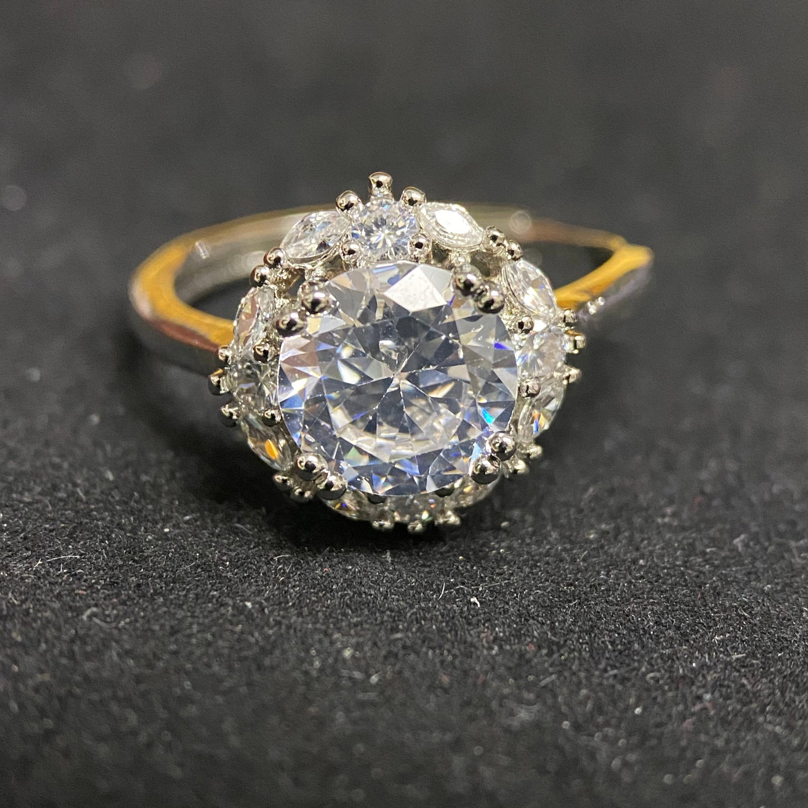 Round Brilliant Cut Sunburst Halo Ring: This high-impact statement ring features a significant 3.0-carat round brilliant-cut center stone. It is framed by a stylized halo of mixed-cut accent stones, creating a brilliant sunburst effect that