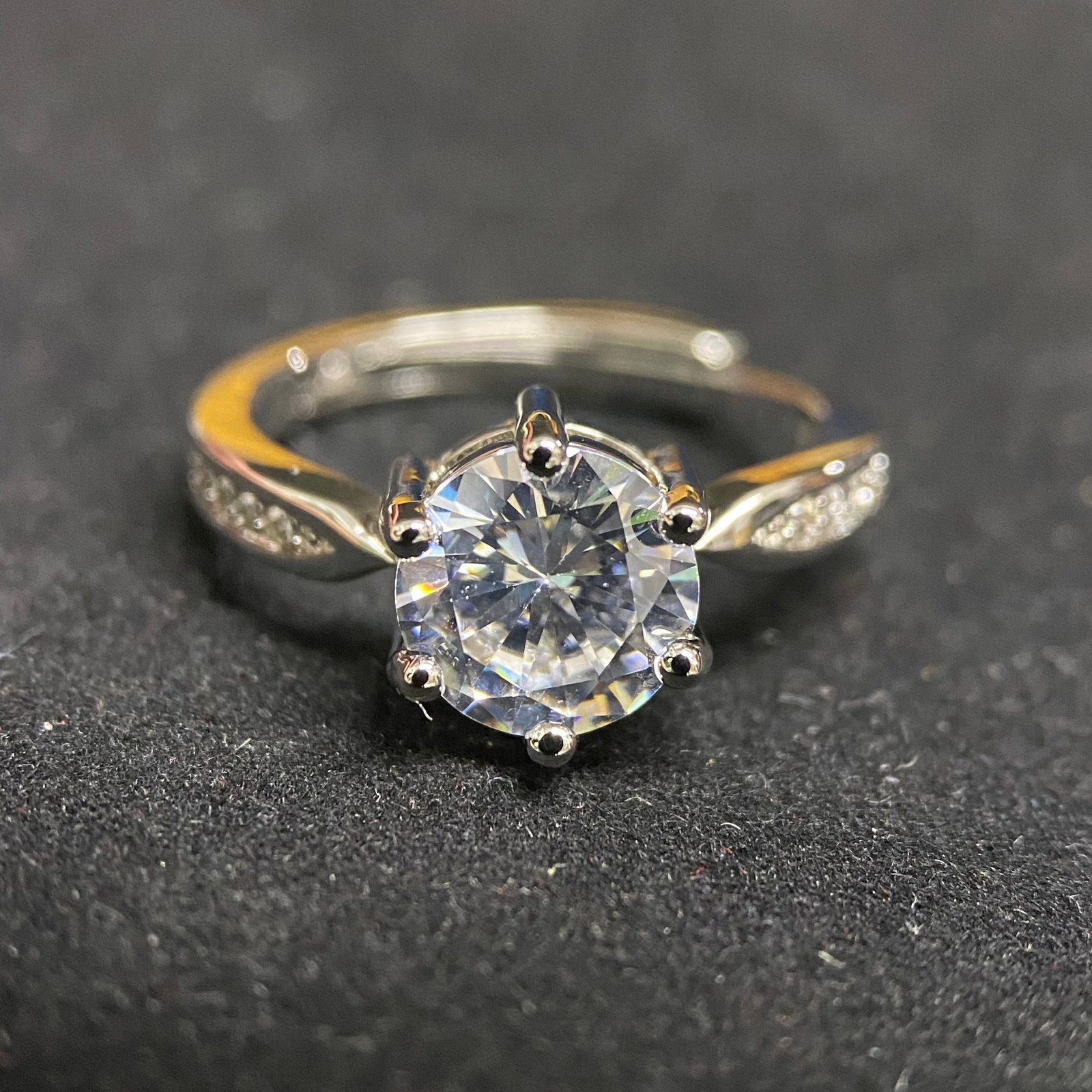 Round Brilliant Cut Six-Prong Accent Ring: A refined and timeless ring featuring a 2.0-carat round brilliant-cut center stone. The gem is held securely by a classic six-prong setting, designed to elevate the stone and maximize light dispersion