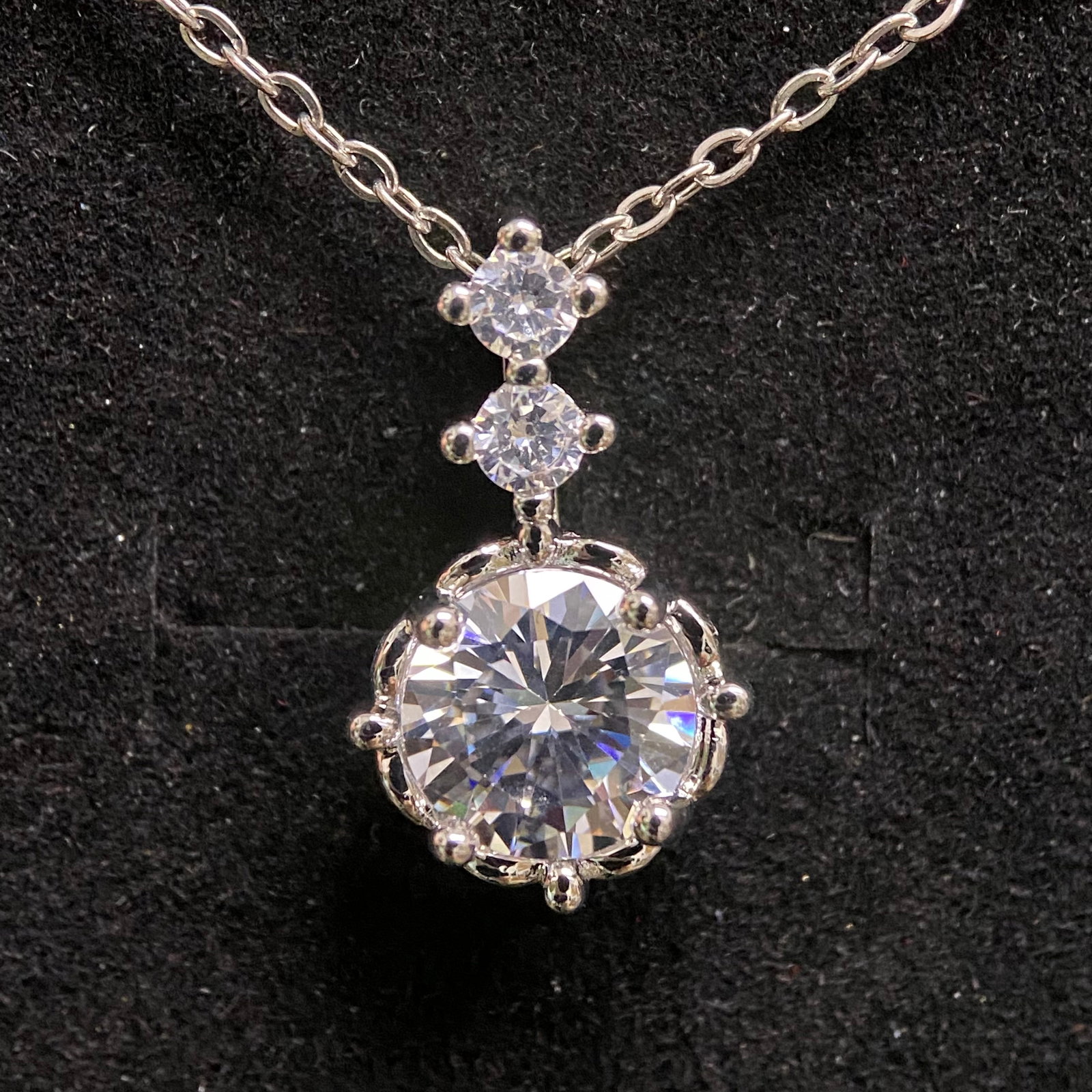 Round Brilliant Cut Solitaire Pendant: An understated and elegant pendant featuring a 1.0-carat round brilliant-cut stone. Held in a refined four-prong setting, the gem is designed to capture and reflect light from every angle. It comes pa