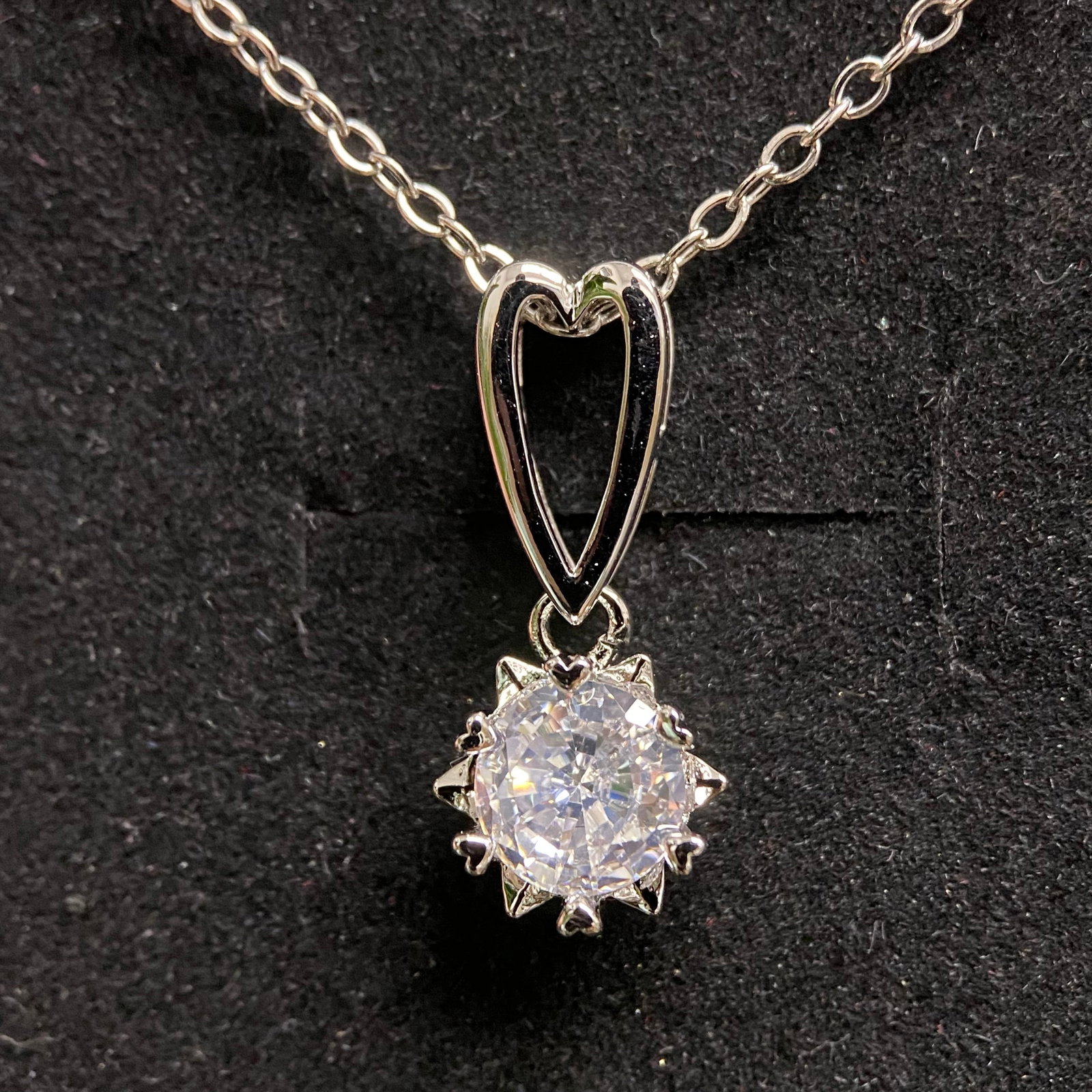 Moissanite Solitaire Pendant Necklace with Heart Bail – 1.0ct D Color, 6.5mm – GRA Certified: Romantic silver-tone necklace featuring a round brilliant-cut moissanite solitaire of 6.5mm / 1.0 carat, D color grade, set in a starburst-style prong setting and suspended from a distinctive open hea