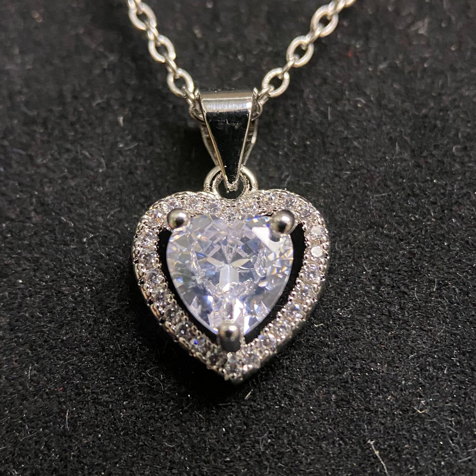 Moissanite Halo Heart Necklace – 3.0ct D, 9x9mm Heart Cut – GRA Certified – Pavé Border: This romantic statement pendant features a substantial 3.0ct heart-cut Moissanite center stone, held securely by a traditional three-prong setting. The stone is framed by a brilliant pavé-set halo, a