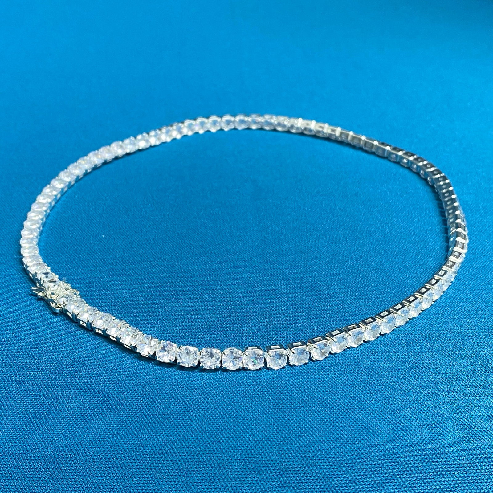 Moissanite Solitaire Necklace – 0.5ct D, 5.0mm Round Cut – GRA Certified – Architectural: This minimalist solitaire pendant features a 0.5ct brilliant round-cut Moissanite stone, held securely by a modern four-prong setting. The architectural basket design is open at the sides to invite ma