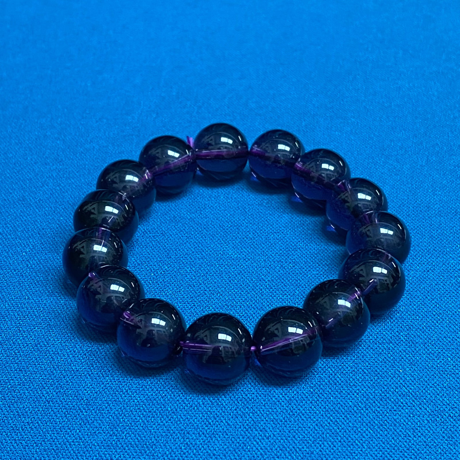 Deep Purple Amethyst Bead Bracelet – Polished Spherical Stones, Stretch Design: This classic beaded bracelet is composed of high-polish, deep purple amethyst-toned spherical stones, each displaying a rich saturation and excellent translucency. The uniform beads are strung on a du