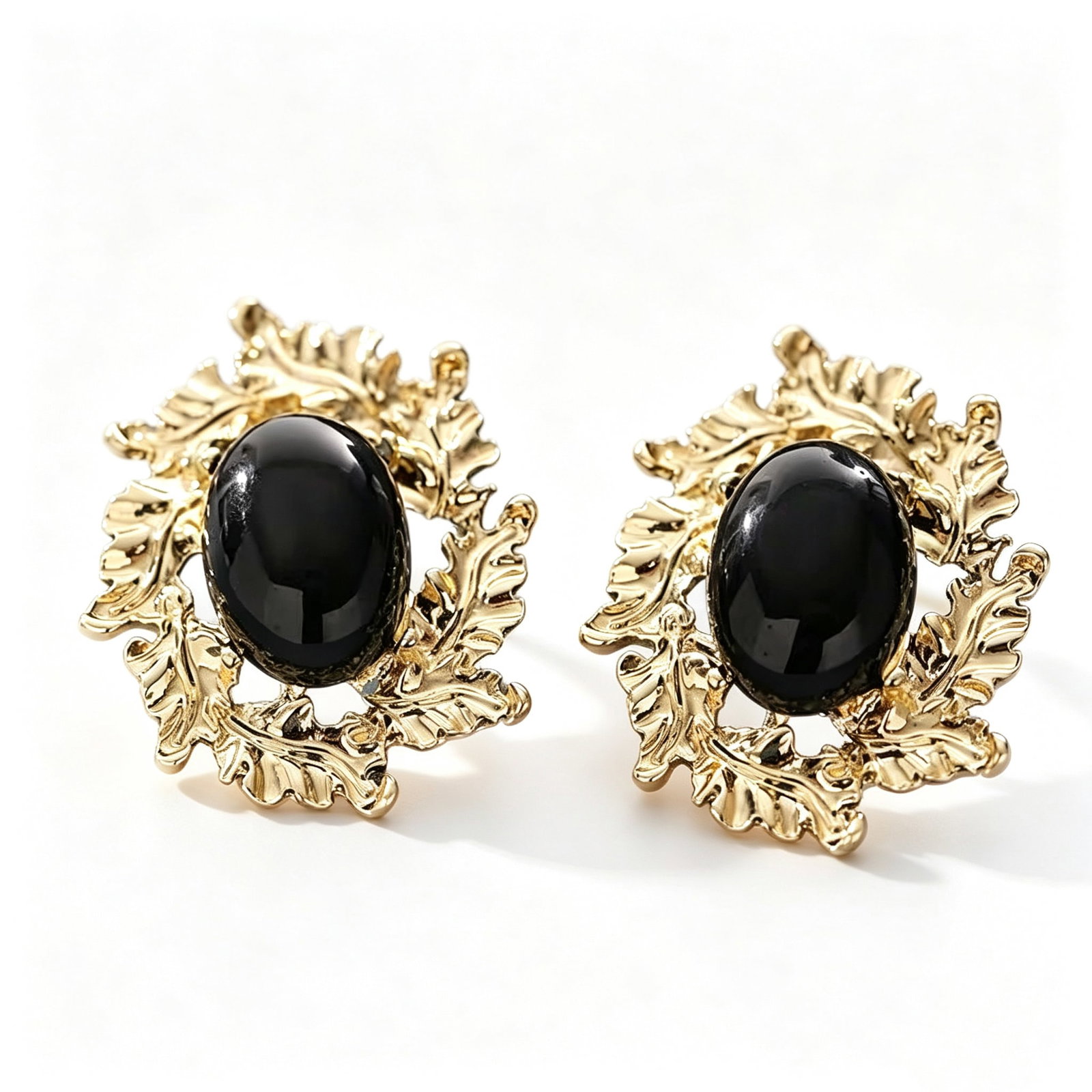 Black Agate Gold-Gilded Leaf Motif Earrings: Pair of earrings featuring black agate cabochon centers accented by ornate gold-gilded leaf motif frames. Elegant vintage-inspired botanical design