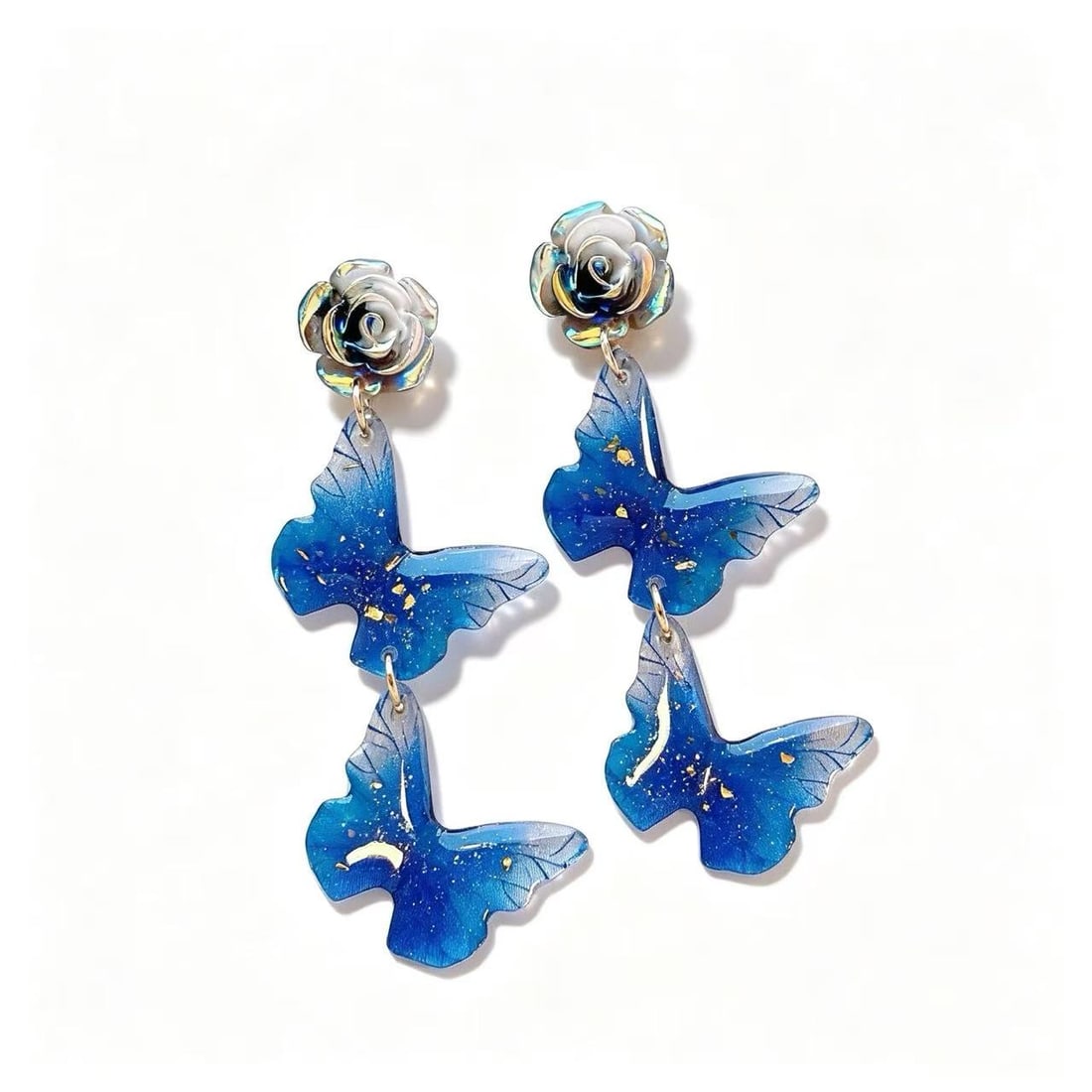 Blue Resin Butterfly Dangle Earrings with Gold Foil Accents and Floral Studs: Decorative dangle earrings featuring layered blue butterfly-shaped resin elements with gold foil-style accents. The earrings are finished with floral-inspired stud tops in a gold-tone setting,