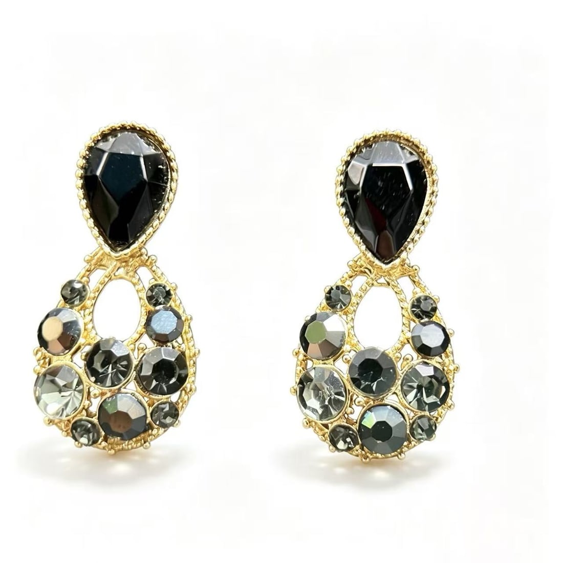 Gold-Gilded Black Crystal Statement Drop Earrings: Pair of statement-style drop earrings featuring faceted black crystal-style elements arranged within openwork gold-gilded frames. Designed with teardrop-shaped upper studs and multi-stone decorative