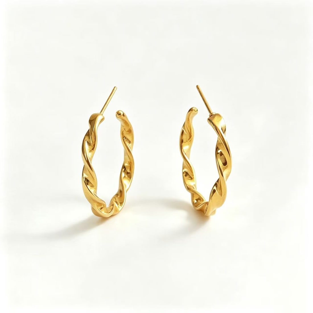 Gold-Gilded Twisted Hoop Earrings: Pair of contemporary twisted hoop earrings featuring an elegant spiral design with polished gold-gilded finish. Minimalist and versatile style suitable for everyday wear or layered jewelry styling.
