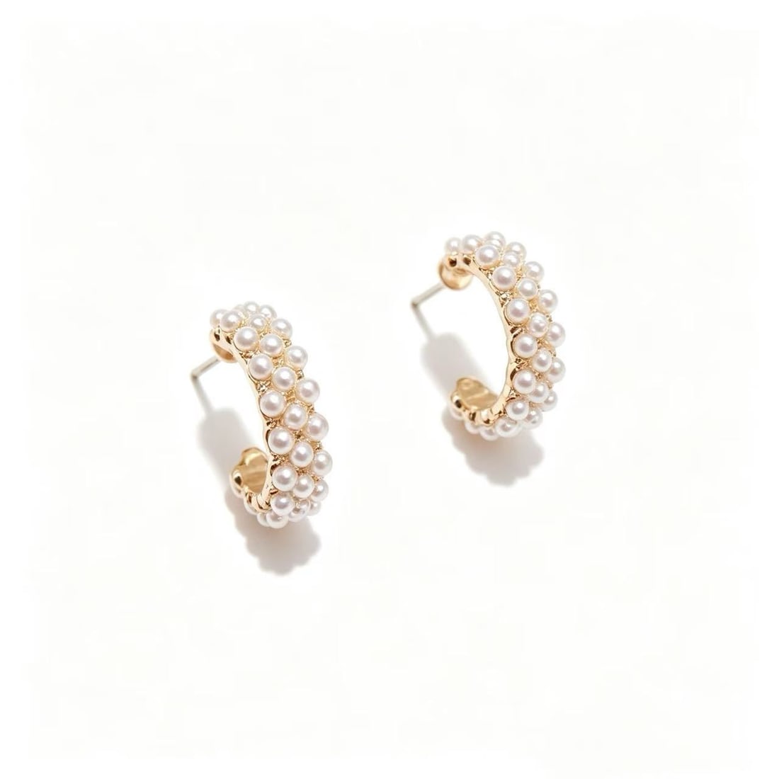 Gold-Gilded Pearl Hoop Earrings: Pair of contemporary hoop earrings featuring rows of small pearl accents mounted on a gold-gilded setting. Elegant and versatile design suitable for both casual and formal styling.