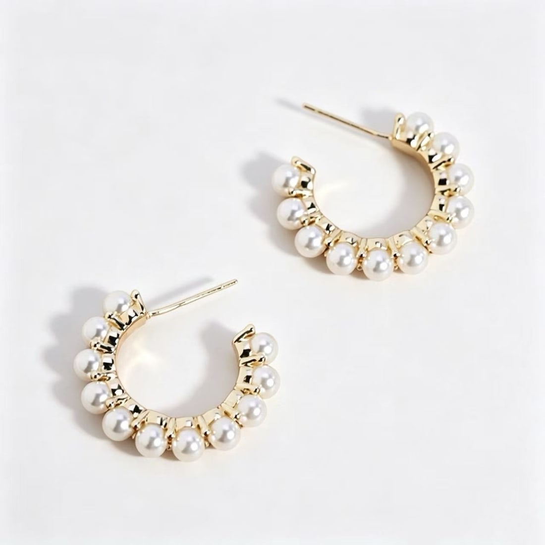 Gold-Gilded Pearl Hoop Earrings: Pair of contemporary hoop earrings featuring evenly spaced pearl accents mounted on a polished gold-gilded setting. Elegant modern design suitable for formal wear, evening styling, or contemporary jew