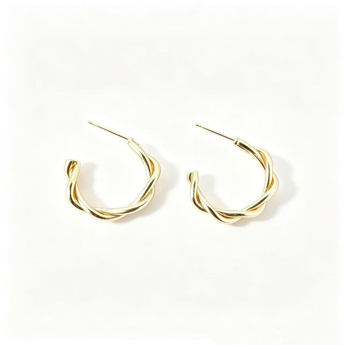 Gold-Gilded Twisted Hoop Earrings: Pair of contemporary twisted hoop earrings featuring an intertwined open-circle design with polished gold-gilded finish. Minimalist yet elegant styling suitable for daily wear, fashion styling, or mod
