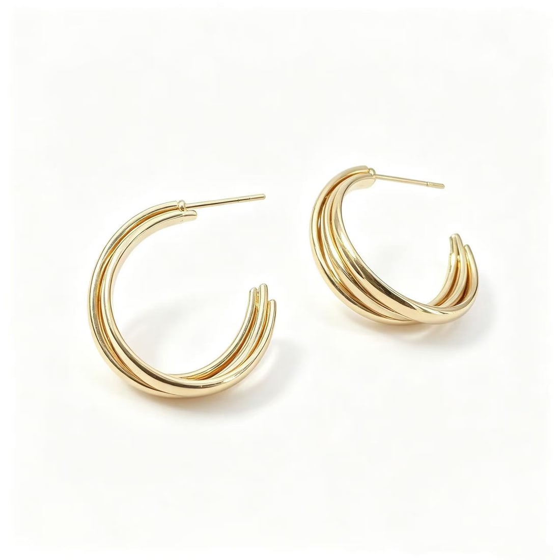 Gold-Gilded Layered Hoop Earrings: Pair of contemporary layered hoop earrings featuring a triple-band curved design with polished gold-gilded finish. Modern sculptural styling suitable for fashion wear, minimalist jewelry collections, 