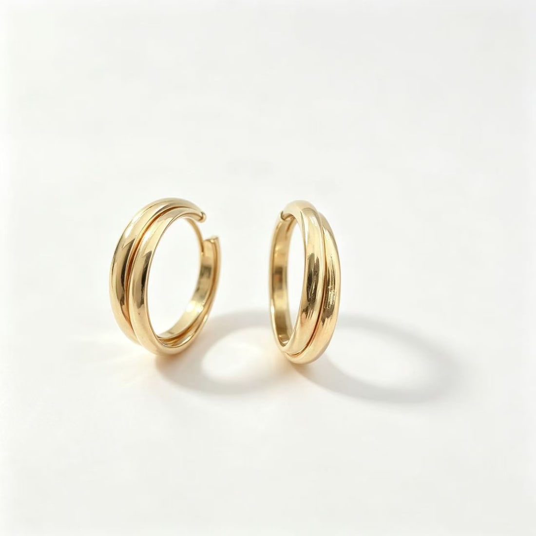 Gold-Gilded Rounded Hoop Earrings: Pair of contemporary rounded hoop earrings featuring a smooth curved profile with polished gold-gilded finish. Elegant minimalist design suitable for everyday wear, modern fashion styling, or contempo