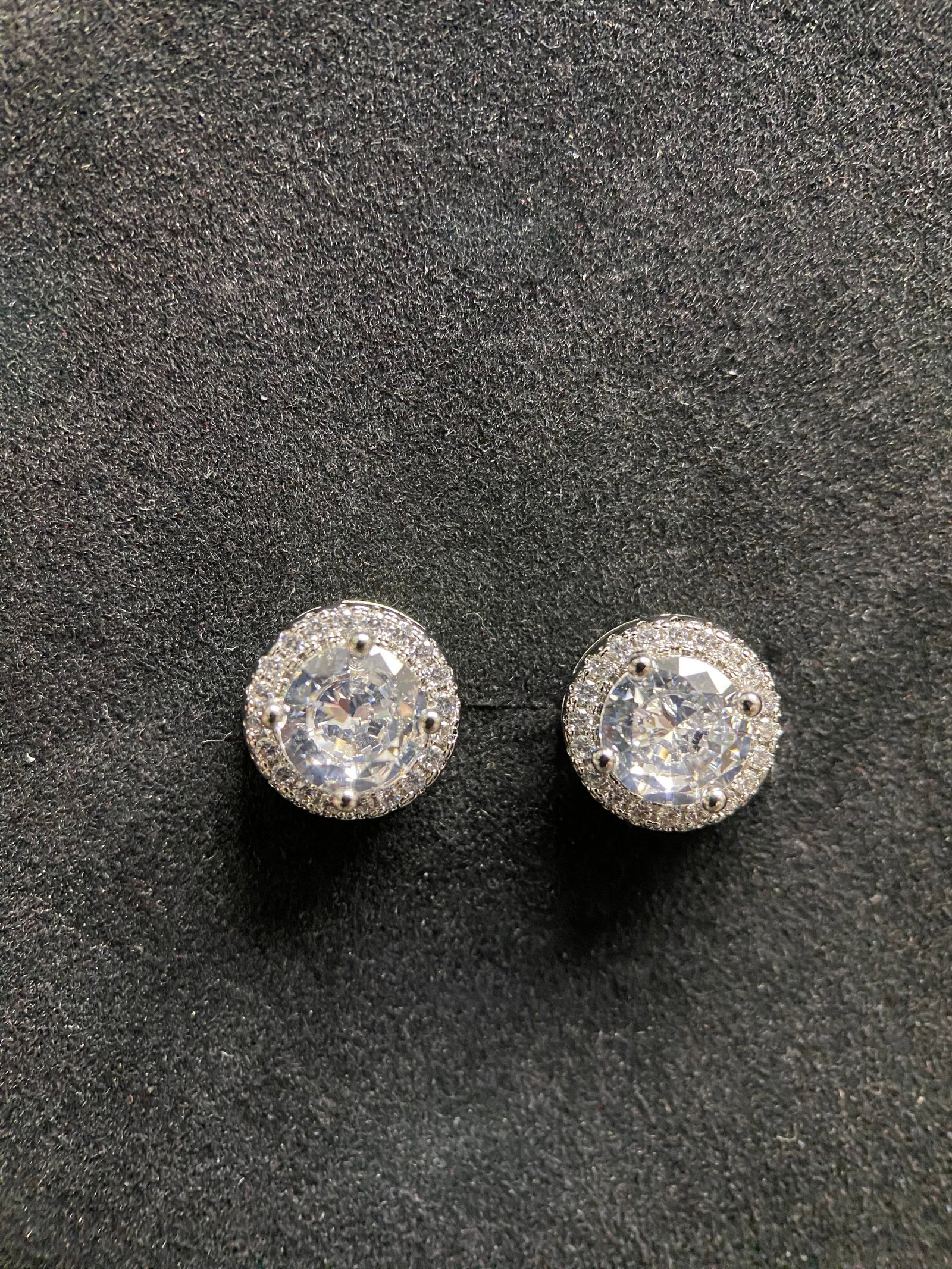1.0ct Round Moissanite Halo Studs, 925: Add a touch of brilliant fire to your style with this classic pair of round brilliant-cut halo stud earrings. Masterfully crafted from high-quality 925 sterling silver, each earring features a strikin