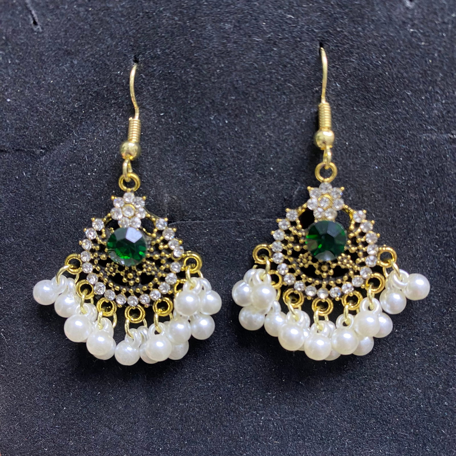 Emerald Crystal Faux Pearl Jhumka Earrings: Channel classic bohemian elegance with these beautiful vintage-inspired chandelier dangle earrings. Crafted in a polished gold tone finish, these statement earrings feature an intricate fan-shaped ope