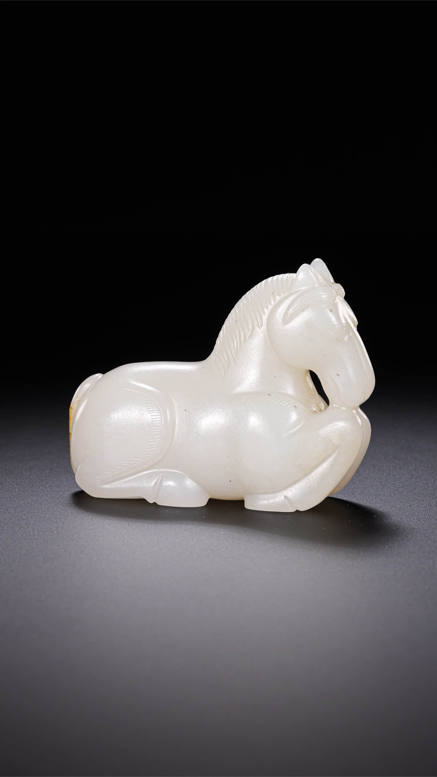 A JADE 'RECLINING HORSE' ORNAMENT: A JADE 'RECLINING HORSE' ORNAMENT Dimensions: Width: 6 cm (2.4 in.), Height: 4.5 cm (1.8 in.). All measurements are approximate.