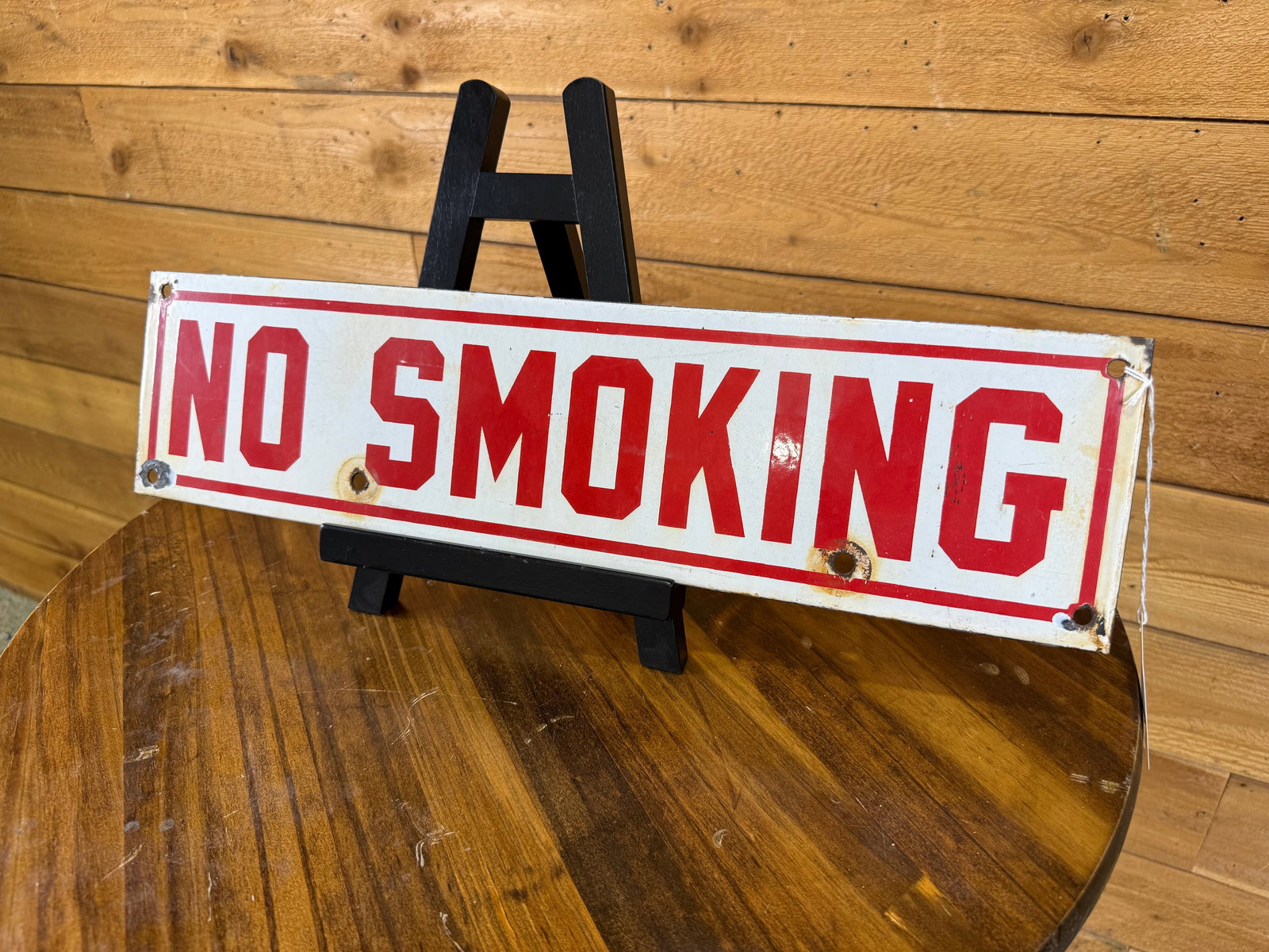 Single Sided Porcelain No Smoking Sign: The sign exhibits moderate wear and rust on the porcelain. There are chips around the mounting holes and perimeter. It has a good gloss and color.