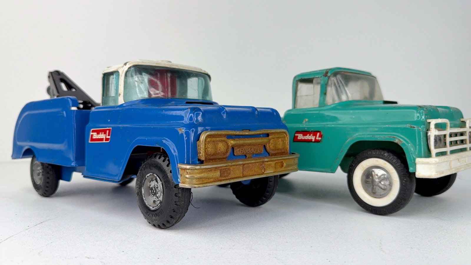 Pair of Buddy L Pickup Truck and Tow Truck: Pair of Buddy L Pressed Steel Trucks including a pickup truck and a tow truck. Both are in good overall condition, showing moderate paint wear consistent with age and use. A desirable pair of classic 
