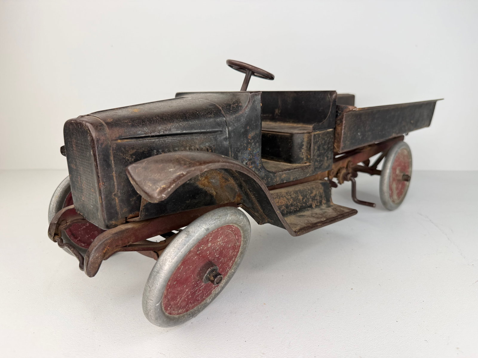 Buddy L pressed steel dump truck: 1920s Buddy L Pressed Steel Dump Truck retaining its original black and red paint along with the original Buddy L label. A highly desirable early pressed steel toy with outstanding vintage character a