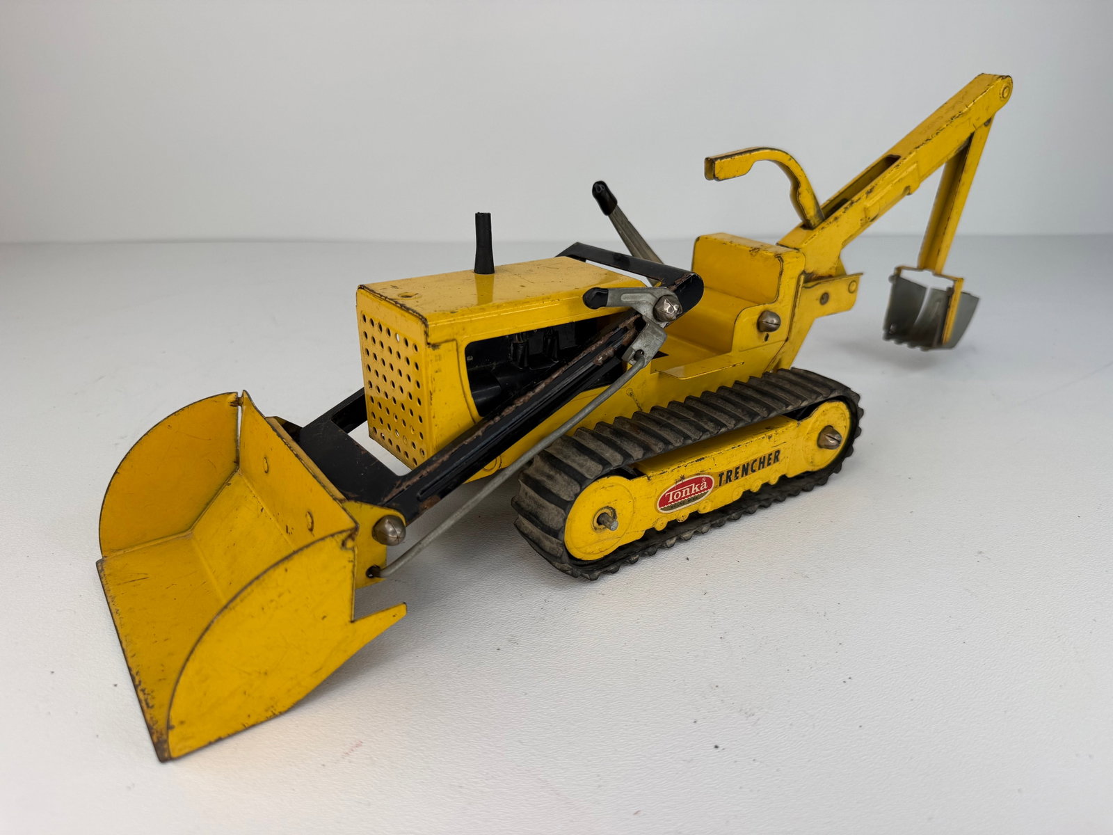 1960s Pressed Steel Tonka Trencher: 1960s Tonka Pressed Steel Trencher featuring the classic Tonka tractor, front-end loader, backhoe, and trencher configuration. In good overall cosmetic condition with honest wear consistent with age a