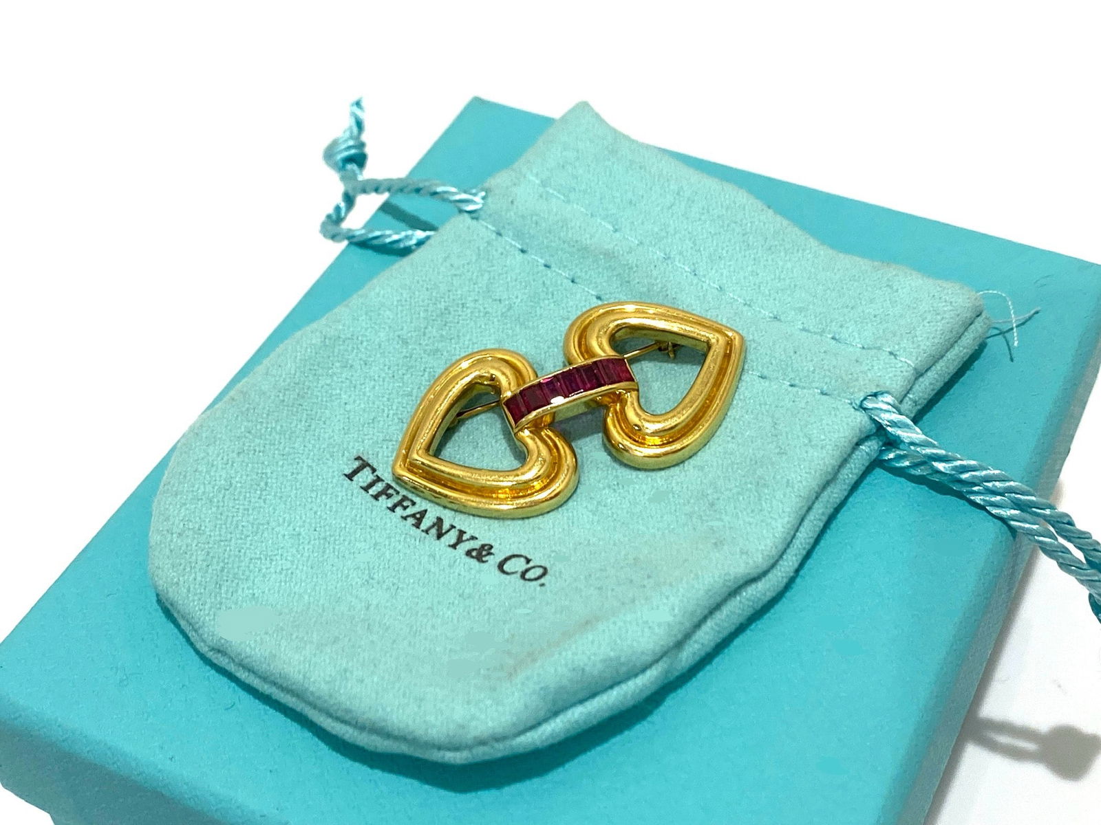 Tiffany & Co. Vintage Double Love Ruby Brooch in 18k Yellow Gold: Condition: Like New Brand: Tiffany & Co. Type: Brooch Metal Purity: 18k Yellow Gold GemStone: RUBY Number of Gemstones: 7 Brooch Dimensions: Length: 1.75"inch Stamp: "T&CO" "18k" Weight: 13.6 grams Co