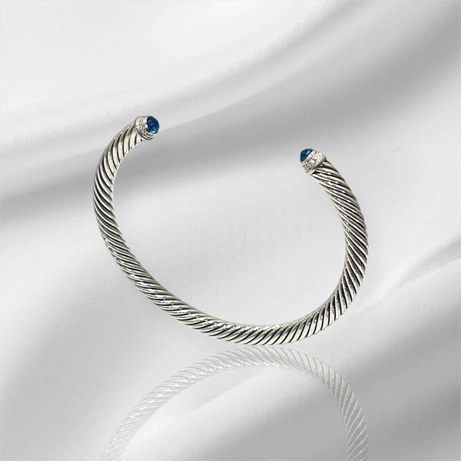 David Yurman Classic Cable Bracelet In Sterling Silver With Blue Topaz And Diamonds: Condition: Like New Brand: David Yurman. Material: 925 Sterling Silver. GemStone: Blue Topaz and Diamond. Diamond Count: 14 Pavé-set diamonds, 0.19 total carat weight. Blue Topaz Count: 2 Topaz, 4mm.