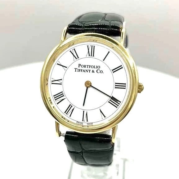 Tiffany & Co. Portfolio 14K Yellow Gold Classic 33mm Round White Dial Watch Qrtz: Specifications Brand: Tiffany & Co. Model: Tiffany & Co. Portfolio. Reference: NA Model: NA Case Material: 14K Yellow Gold. Case Size: 33mm. Dial: Roman Numerals and White Color Dial. Bezel: 14K Gold.
