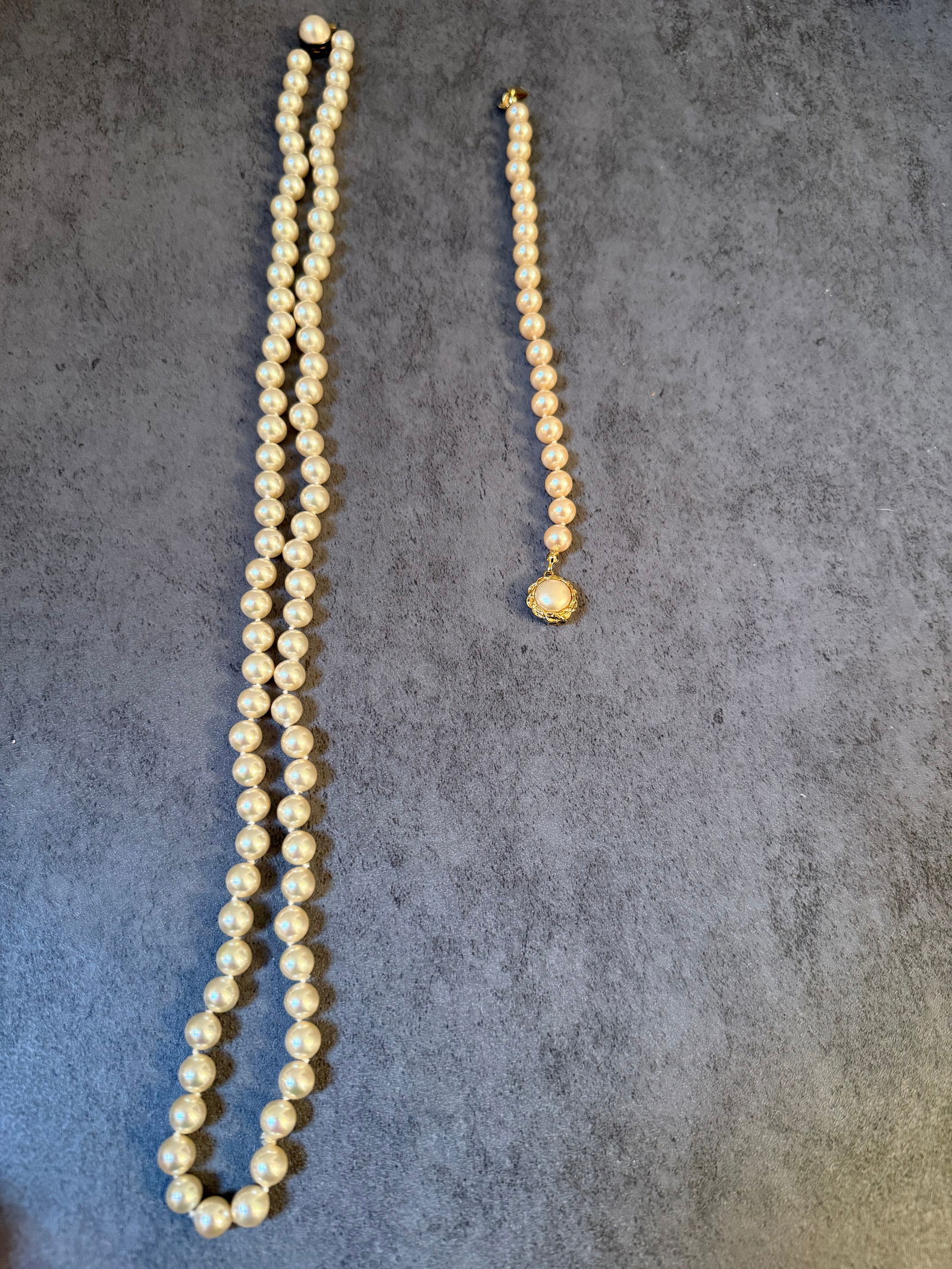 Group of Two Vintage Pearl Jewelry Pieces: A group of two vintage pearl jewelry pieces, including one necklace and one bracelet.The first piece is a classic pearl necklace composed of evenly sized round pearls strung in a single strand. The pe
