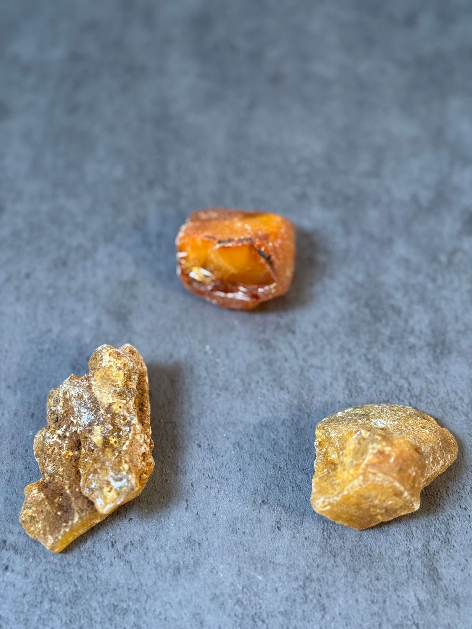 Three resin chunks: A mixed vintage material lot consisting of several amber-toned resin chunks or cut sections, along with miscellaneous small components.The materials appear to be early resin or similar synthetic mater