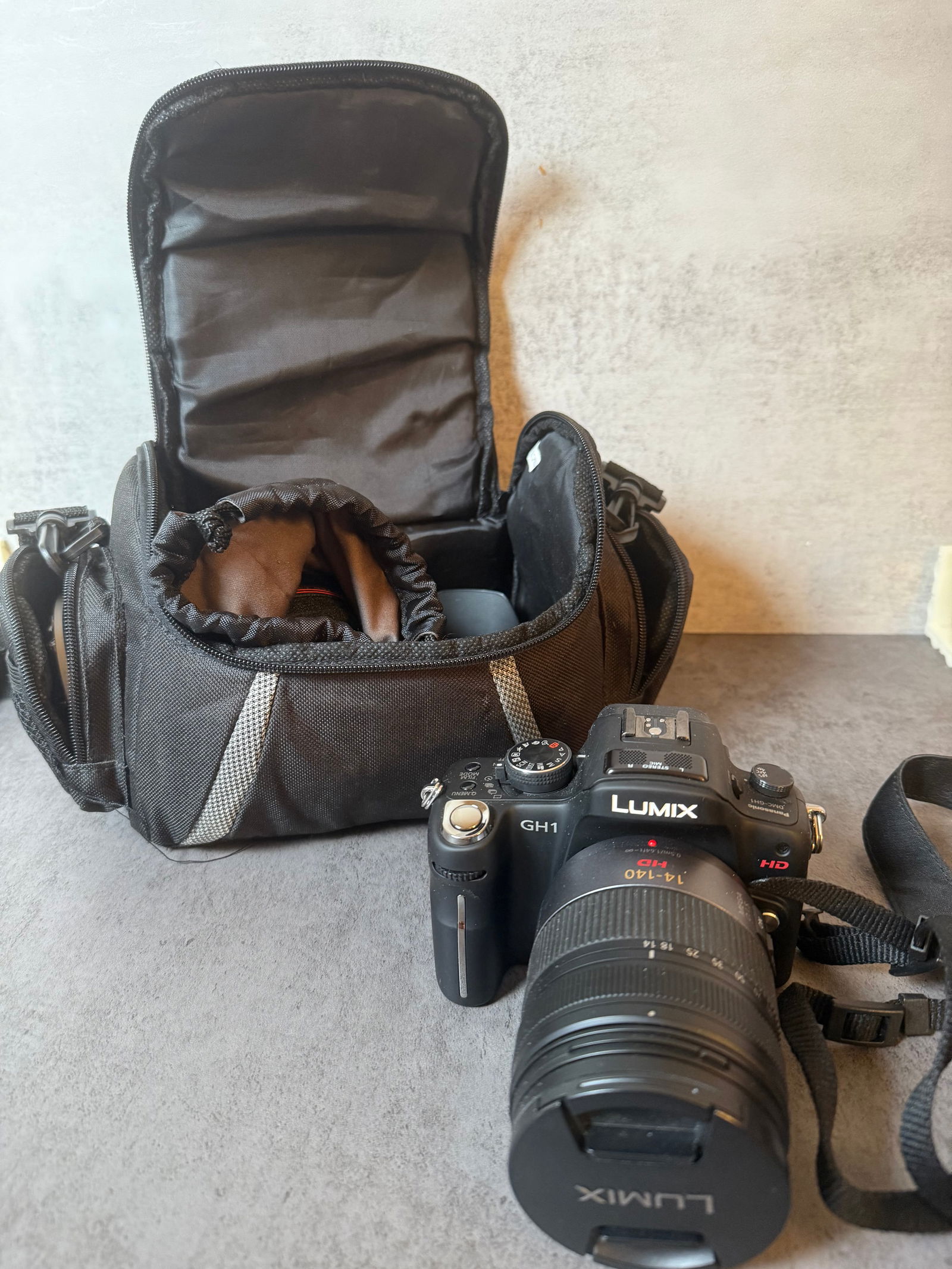 Panasonic Lumix GH1 Mirrorless Camera with Zoom Lens & Camera Bag: A Panasonic Lumix GH1 mirrorless digital camera offered with a zoom lens and a padded camera bag. The camera features a compact interchangeable-lens system design and is known for its early HD video c
