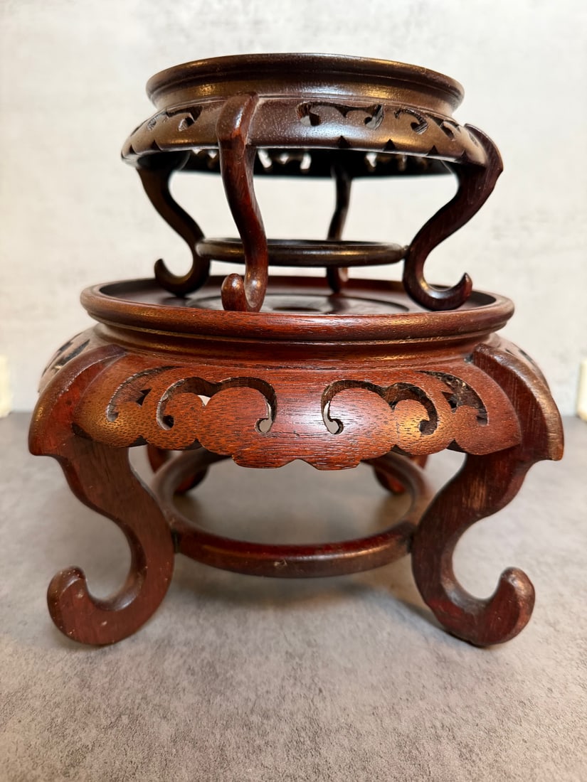 Two Chinese Carved Hardwood Display Stands: Two separate Chinese carved hardwood display stands, each of circular form with openwork scroll apron and curved legs. Suitable for displaying vases, bowls, or other decorative objects.Finished in a