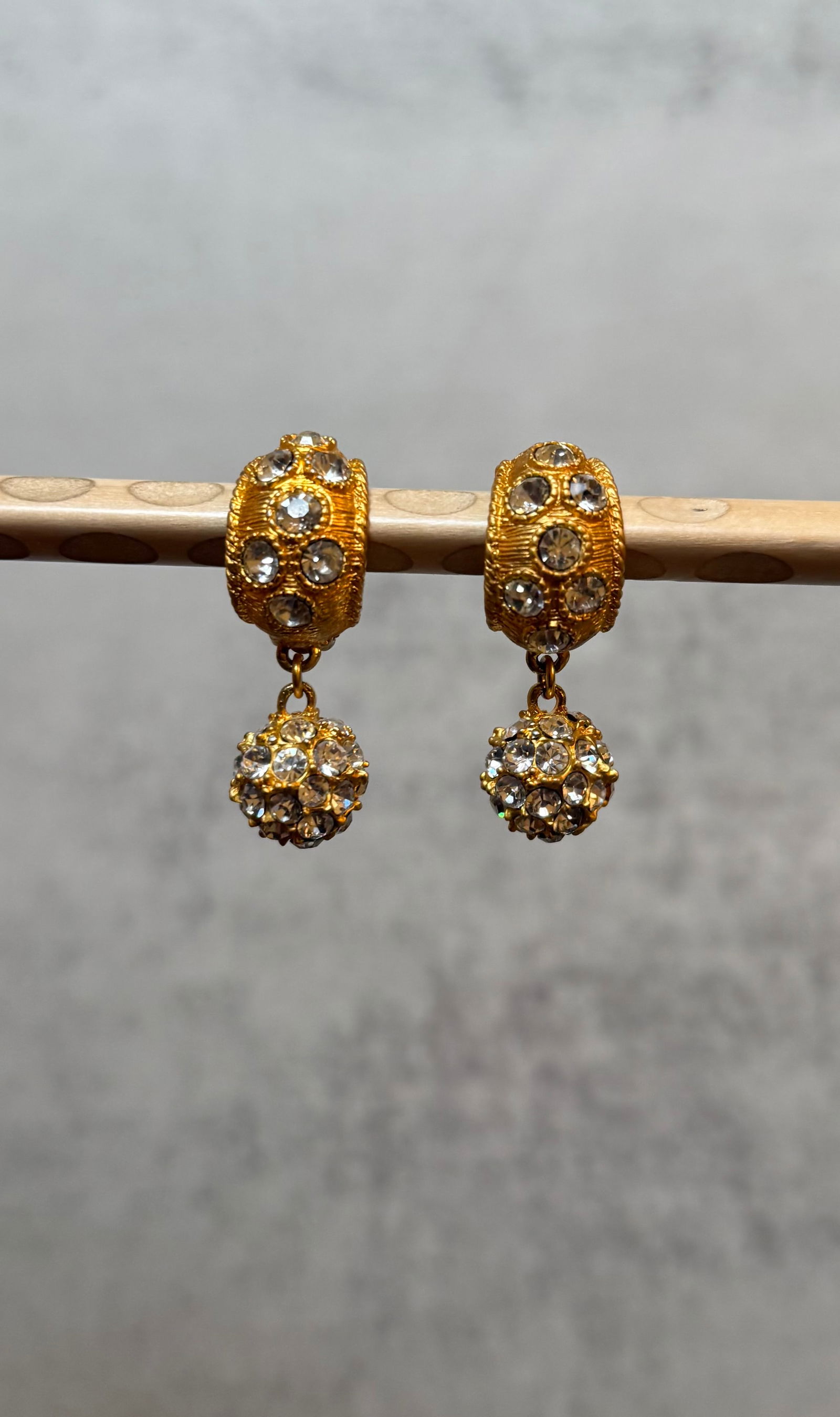 Pair of Gold Tone Rhinestone Ball Drop Clip-On Earrings: A pair of gold tone clip-on drop earrings, each with a rhinestone-set textured hoop clip suspending a pav?? rhinestone ball pendant.