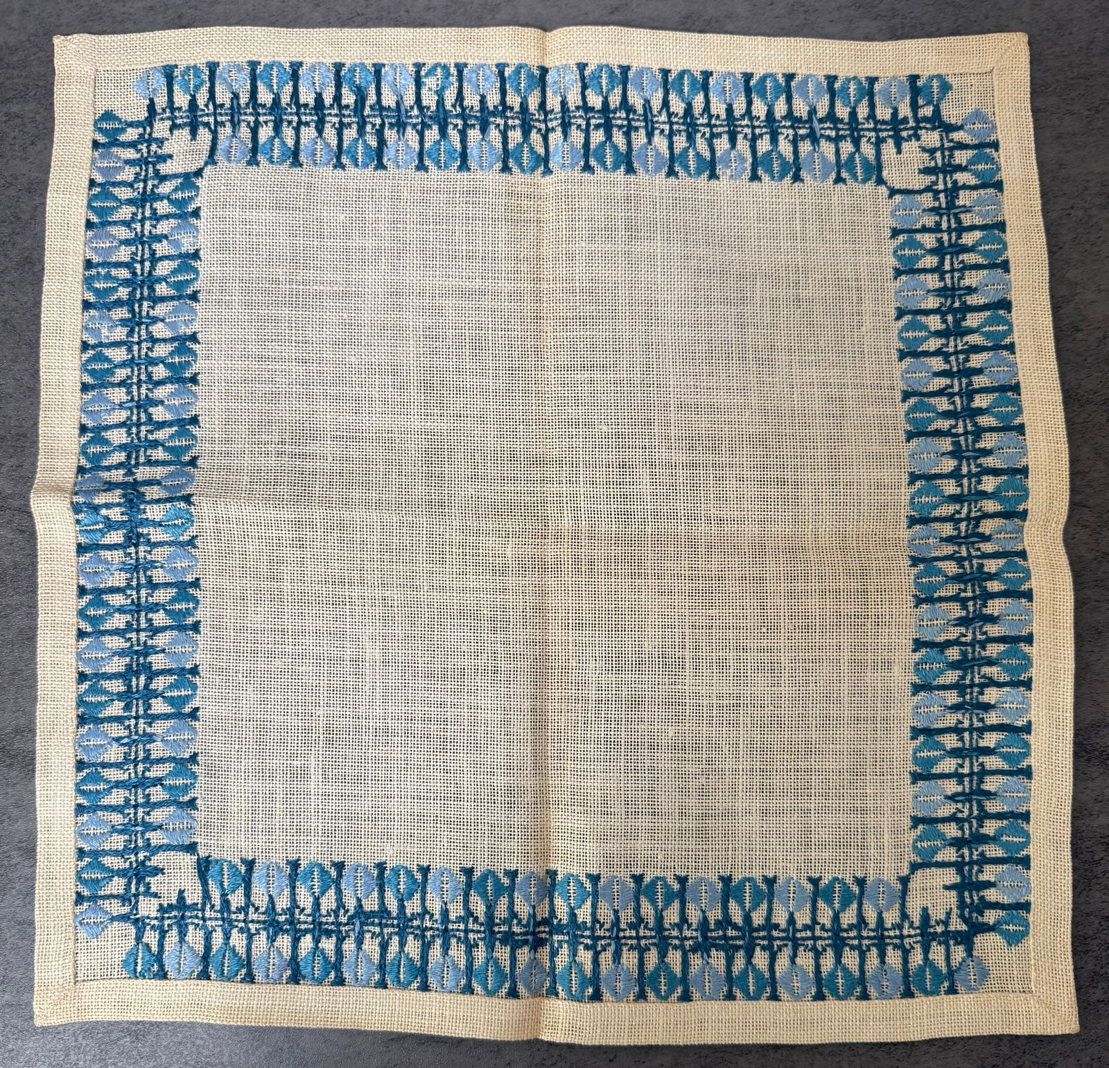 Vintage Hand Embroidered Linen Openwork Table Mat with Blue Border: A vintage hand-embroidered linen table mat featuring an openwork border design worked in blue thread. The decorative border displays a repeating geometric pattern created using drawn thread and