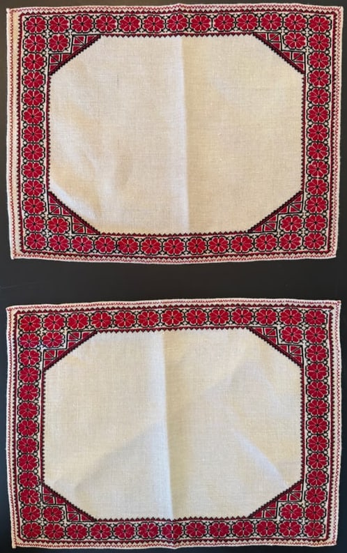 Pair Vintage Eastern European Hand-Embroidered Linen Placemats, 17 x 13 in: A pair of vintage hand-embroidered linen placemats featuring traditional Eastern European cross-stitch decoration. The pieces display a red and black floral geometric border surrounding a central