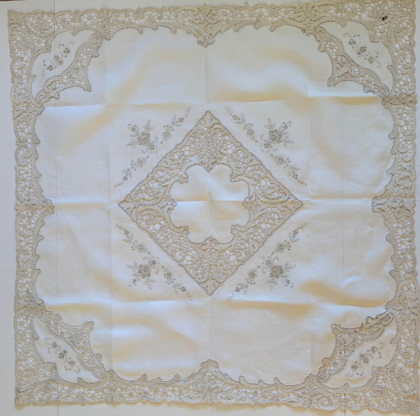 Vintage Hand Embroidered Linen Tablecloth with Needle Lace Inserts, 34 x 34 in: Vintage linen tablecloth featuring hand embroidery and decorative needle lace inserts. The design includes elaborate lace panels at the corners and center with delicate floral embroidery on natural