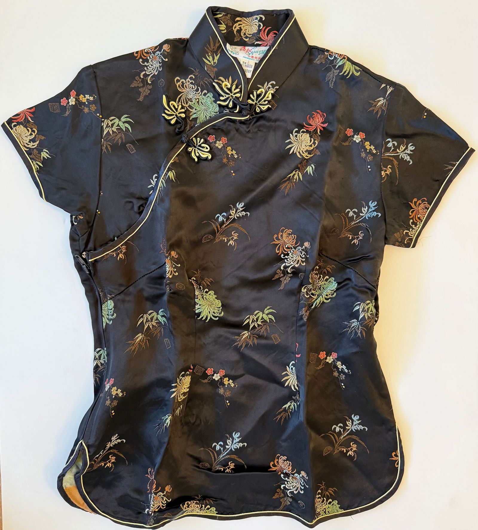 Vintage Chinese Black Rayon Embroidered Cheongsam Qipao Style Blouse, Hangzhou: Vintage Chinese cheongsam (qipao) style short sleeve blouse in black rayon fabric decorated with colorful floral embroidery throughout. Traditional frog closures at the front. Interior label reads