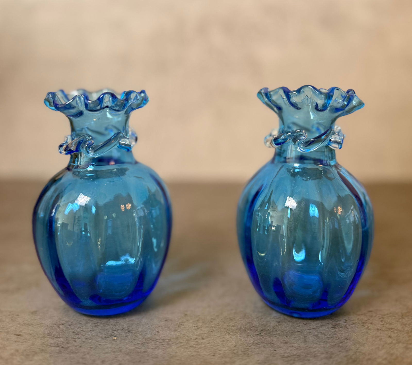 Pair of Blue Art Glass Miniature Vases: Pair of decorative blue art glass miniature vases with ruffled rims and applied glass decoration around the neck. Transparent cobalt tone glass with rounded bodies. Each approx. 4.5 in H x 3 in W.