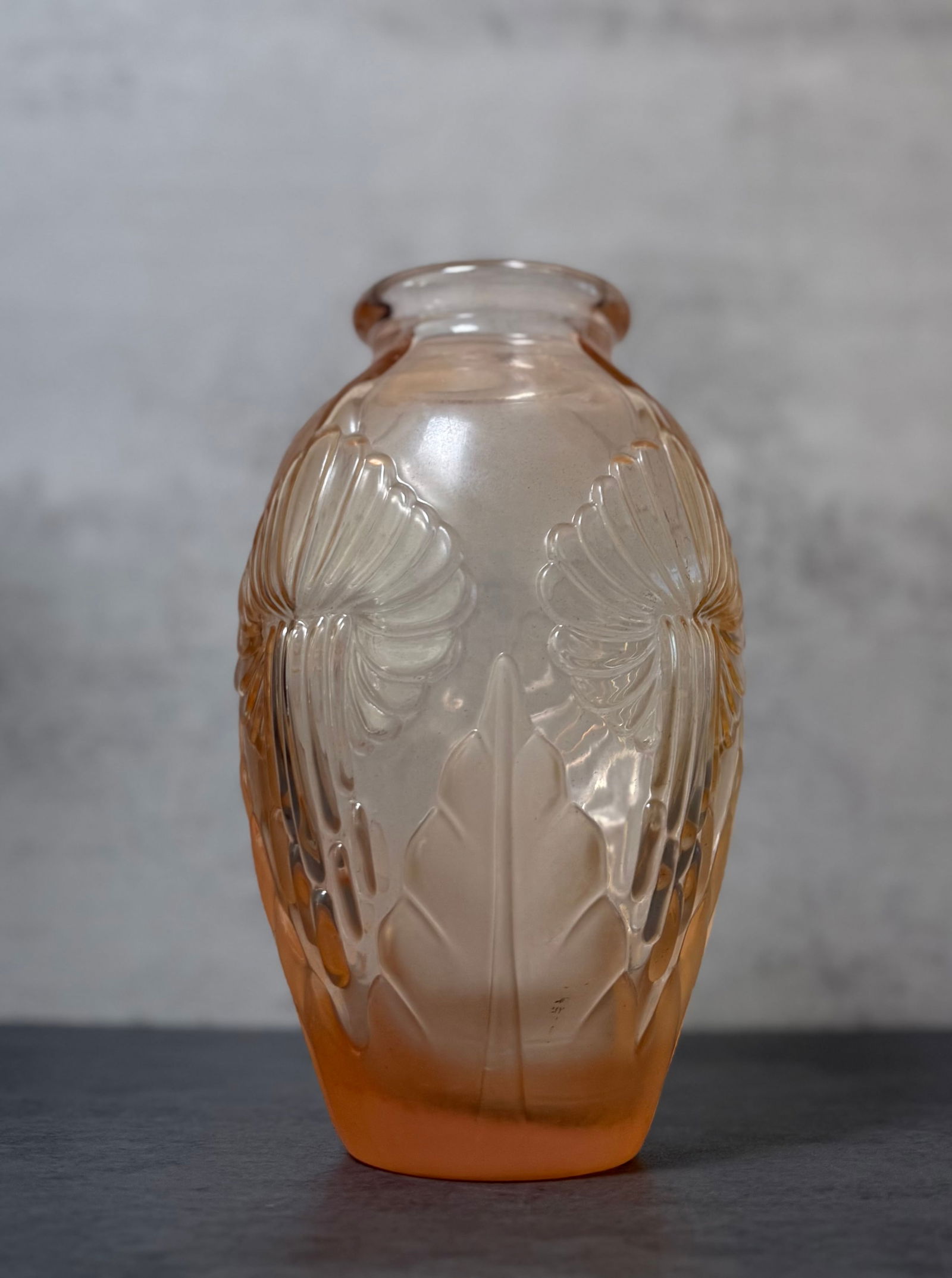 Art Deco Amber Pressed Glass Relief Decorated Vase: Decorative Art Deco style pressed glass vase in a warm amber to peach tone glass, the body of tapered ovoid form with a broad circular mouth and molded relief decoration throughout. The exterior is