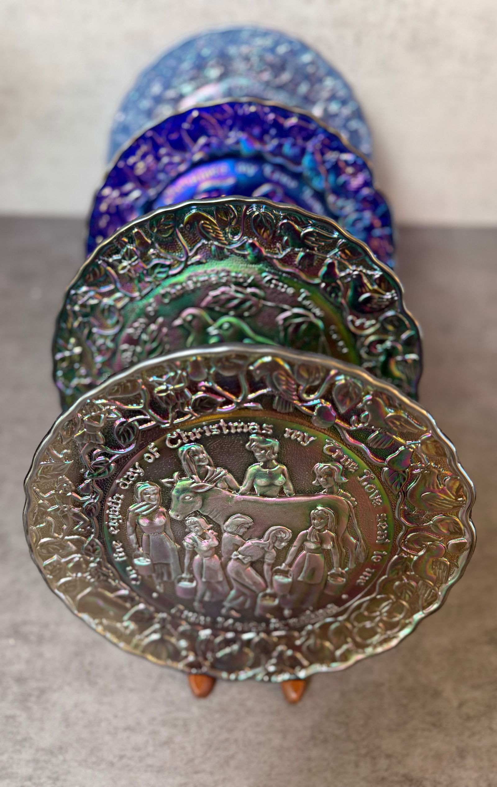 Fenton Carnival Glass “12 Days of Christmas” Collector Plates, Lot of 4: Group of four iridescent carnival glass collector plates from the “12 Days of Christmas” series by Fenton Art Glass. Each plate features richly molded figural decoration illustrating scenes