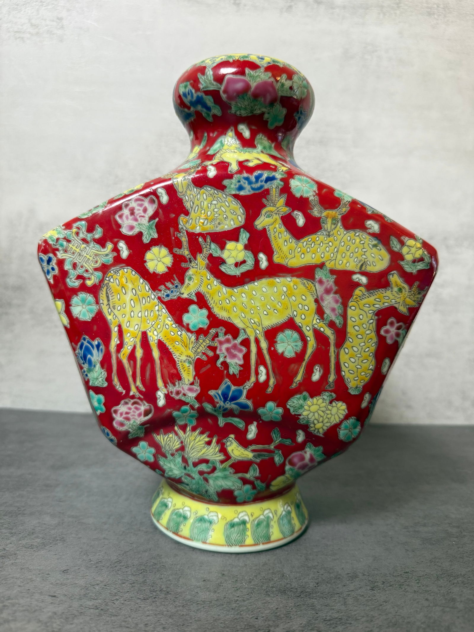 Chinese Famille Rose Deer Vase with Apocryphal Qianlong Mark, 20th Century: Chinese porcelain vase decorated in famille rose enamels with deer among flowering plants against a vibrant iron-red ground. The neck similarly decorated with fruit and foliage motifs, and the foot