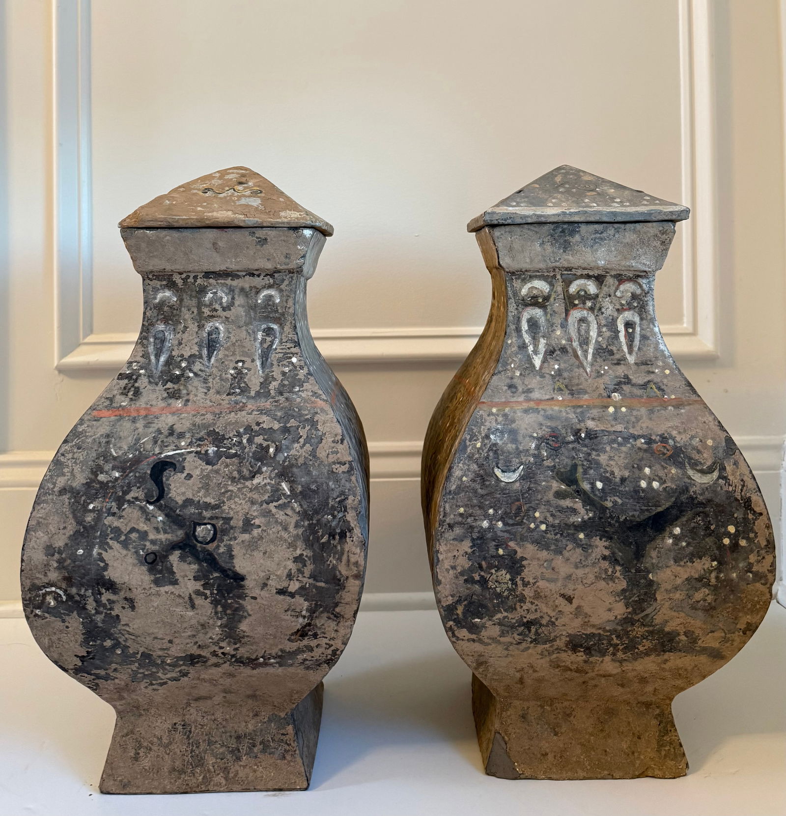 Pair of Chinese Painted Earthenware Jars with Bird Decoration: A pair of Chinese earthenware jars with domed covers, decorated with painted bird motifs and simple geometric ornament around the shoulders. The vessels have a rustic surface with traces of pigment