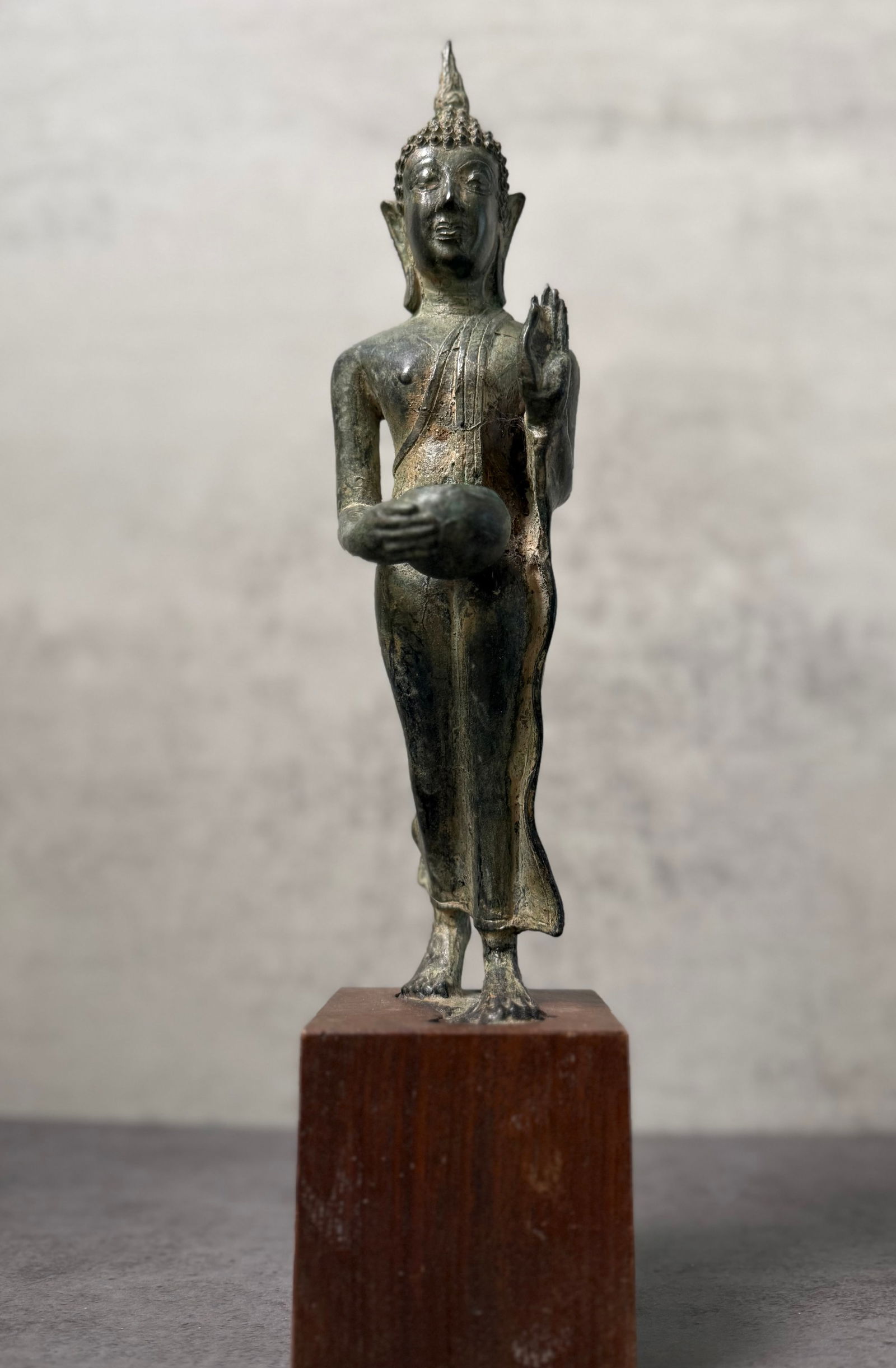 Antique Southeast Asian Bronze Walking Buddha Figure, Thai Sukhothai Style: Antique bronze figure depicting the Buddha in the classic Southeast Asian walking posture, with the right hand raised in the gesture of reassurance known as abhayamudra. This graceful stance is