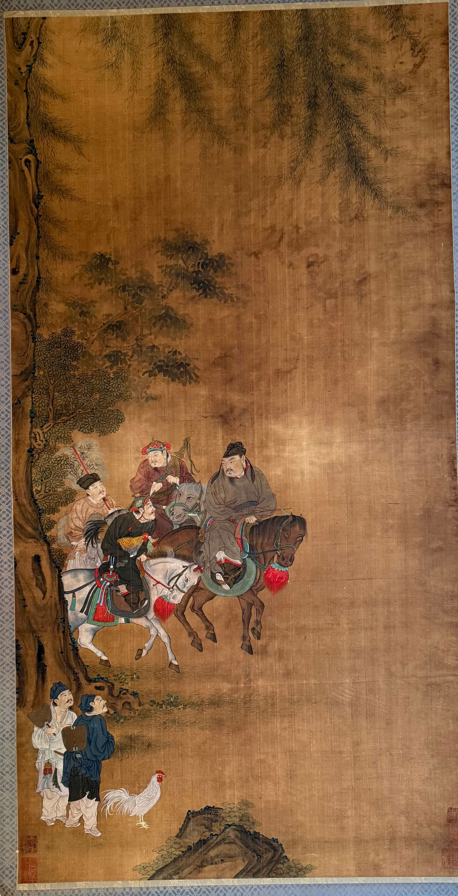 Antique Chinese Silk Scroll Painting, Figural Procession with Horses, Attendants and Rooster: A large antique Chinese hand-painted silk scroll depicting a dynamic procession scene with elegantly dressed figures on horseback accompanied by attendants on foot, set beneath ancient pine and