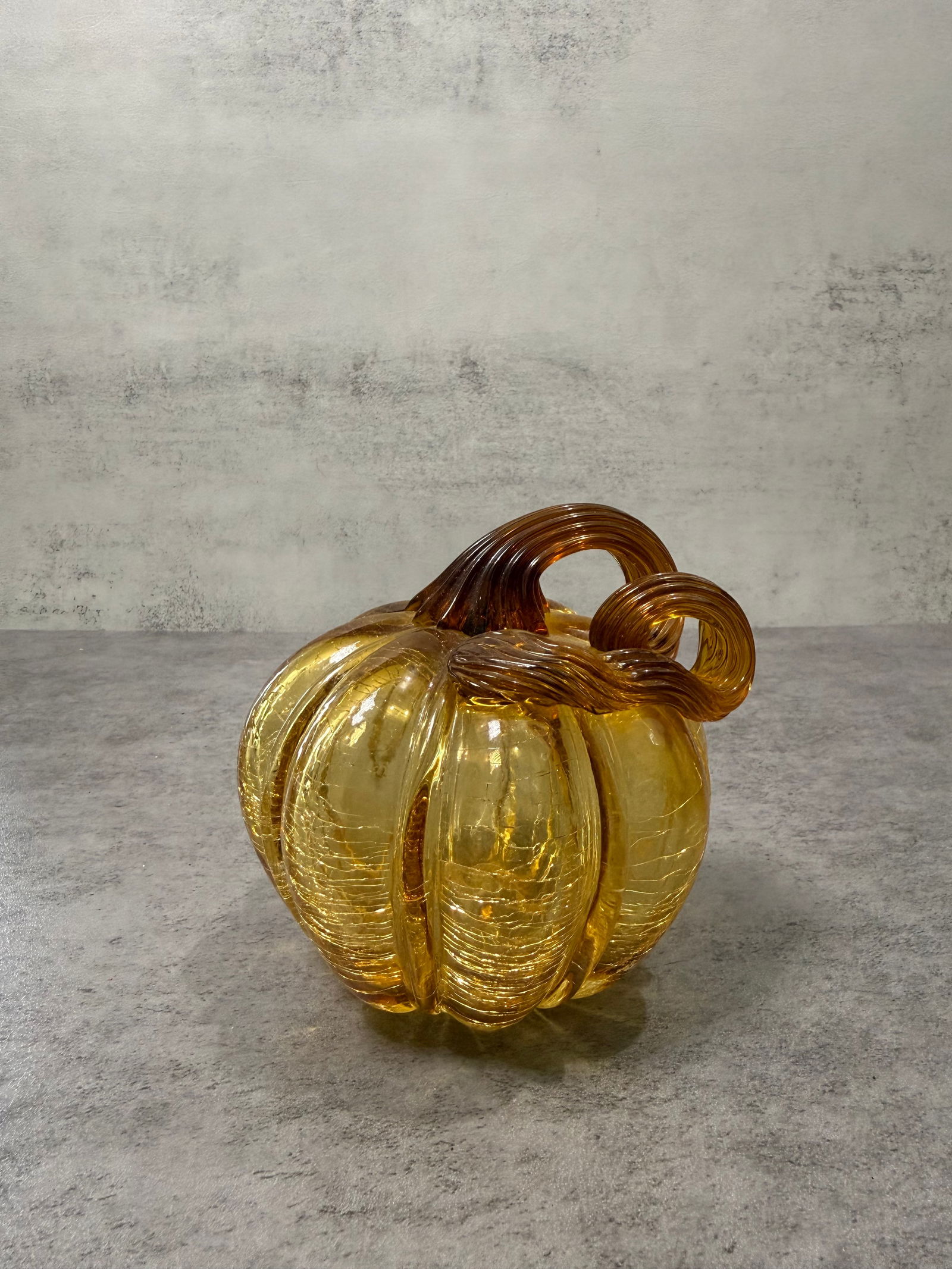 Art Glass Amber Crackle Glass Pumpkin Figurine Blown Glass Fall Decor: Decorative blown art glass pumpkin in warm amber/golden color with crackle glass texture throughout. Features ribbed coiled stem in darker amber. Beautiful light transmission and organic form.