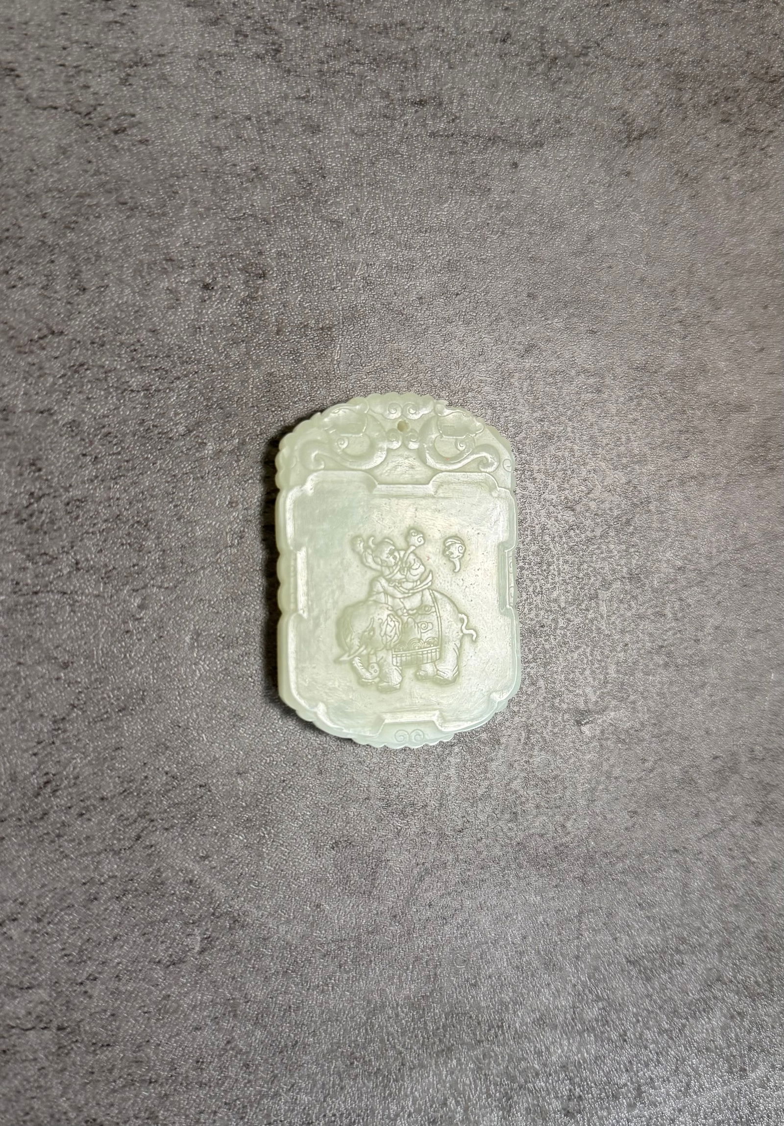 Chinese Carved Jade Pendant Plaque with Boy Riding Elephant Motif: A Chinese carved jade pendant plaque featuring a boy riding an elephant while holding a ruyi scepter. The carving symbolizes auspicious blessings, as the elephant represents peace and prosperity