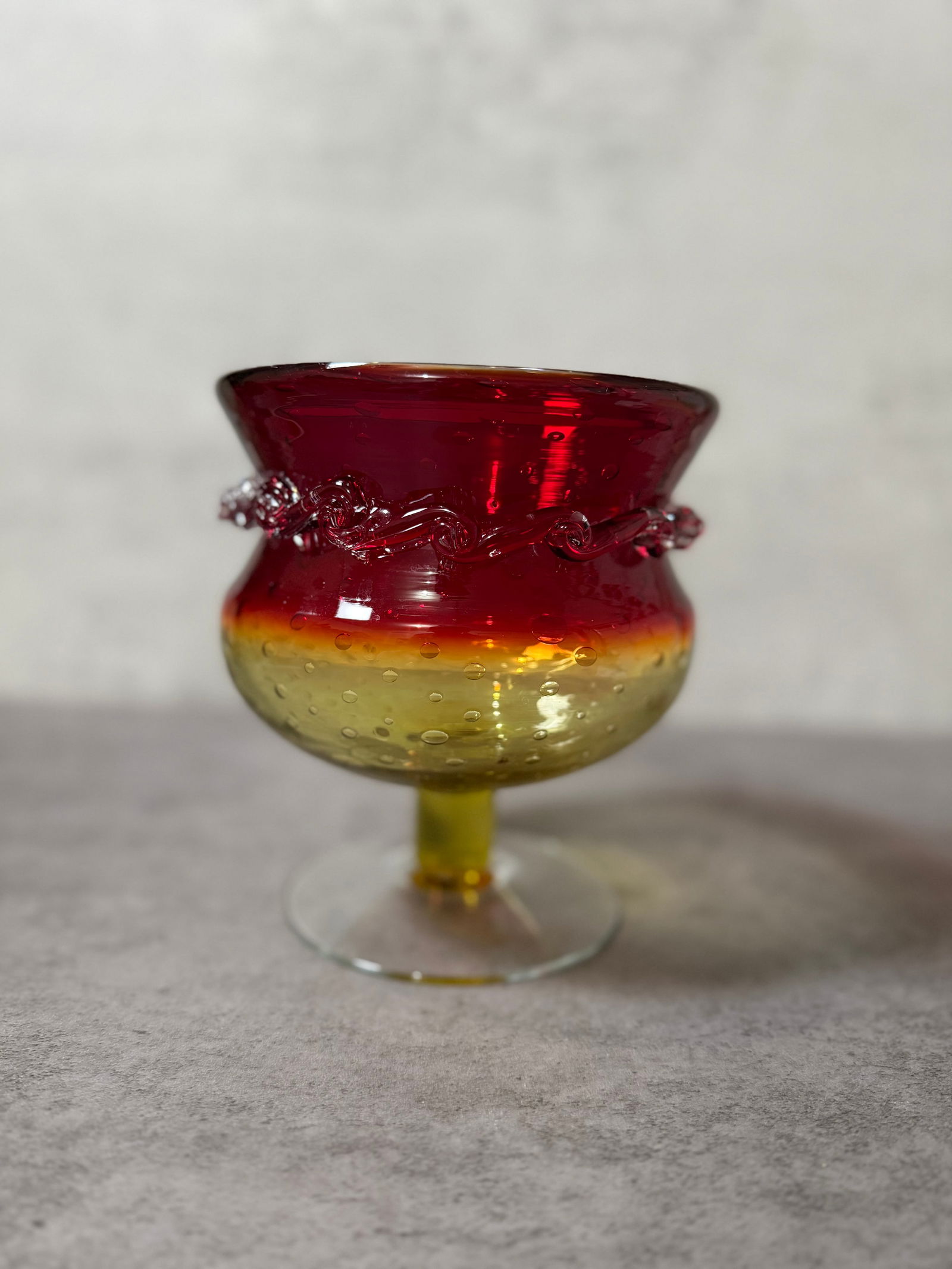 Vintage Amberina Art Glass Compote, Red to Yellow Gradient with Applied Trail Decoration: A striking vintage art glass compote featuring a vibrant amberina color transition from deep ruby red to warm golden yellow.The bowl is accented with applied trailing decoration encircling the body,