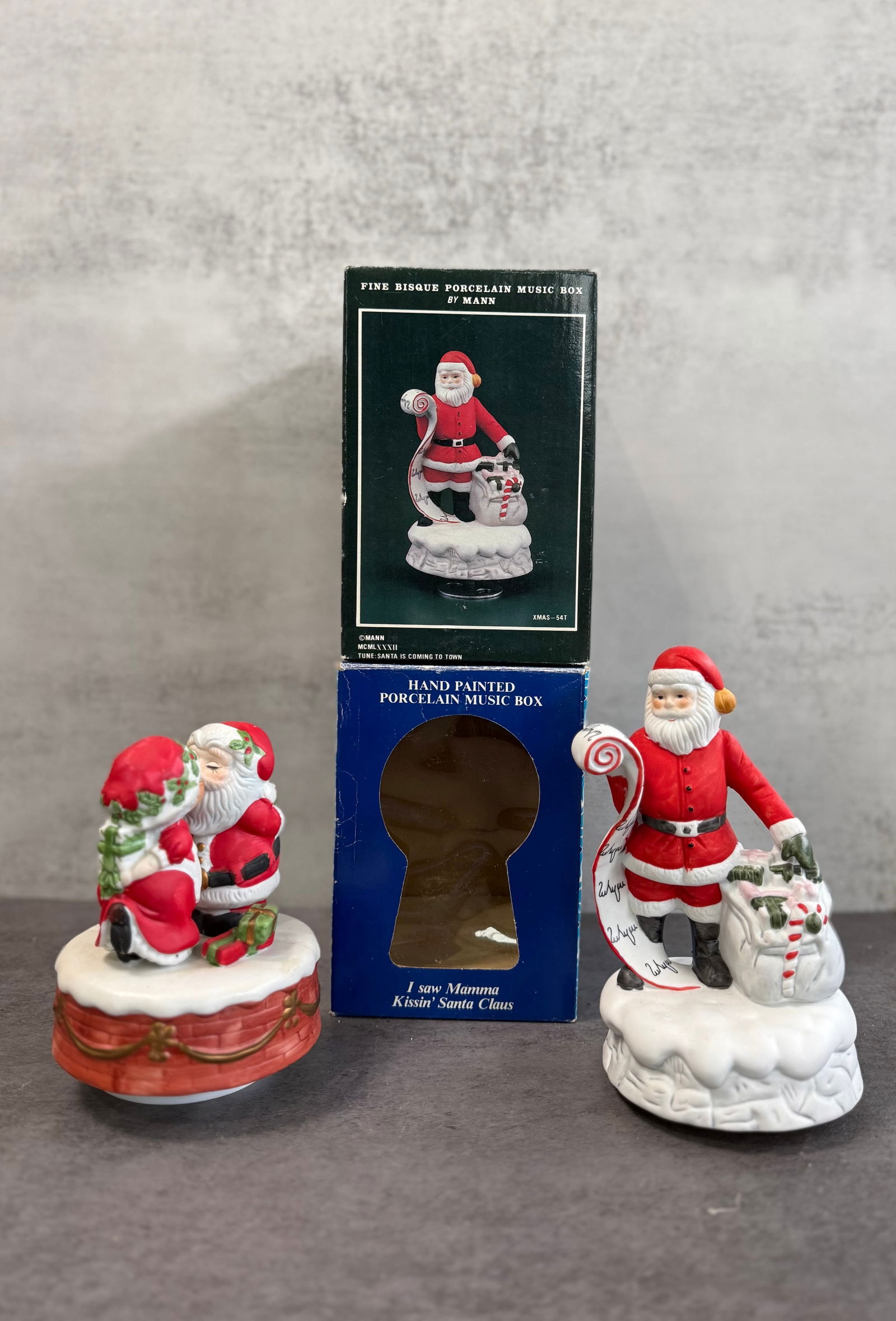 Vintage Porcelain Santa Claus Music Box Lot, Hand Painted Holiday Figurines: A charming lot of two vintage porcelain Santa Claus music boxes, both hand-painted with festive holiday details.One features Santa holding a scroll and gift sack, accompanied by its original box