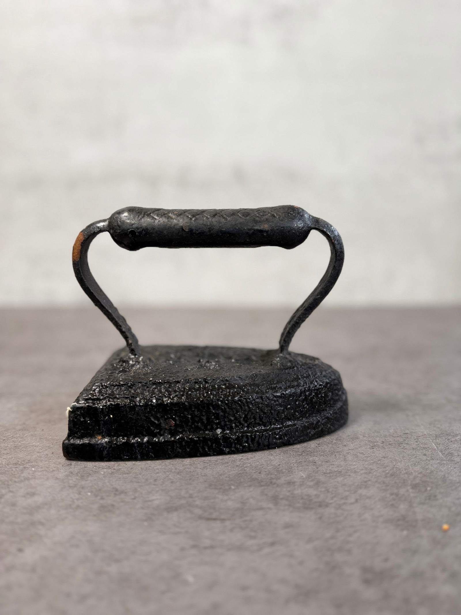 Antique Cast Iron Sad Iron with Eagle Motif, Primitive Rustic Decor: An antique cast iron sad iron featuring a distinctive eagle motif on the body.This early household tool was traditionally heated for pressing garments and now serves as a rustic decorative object. The