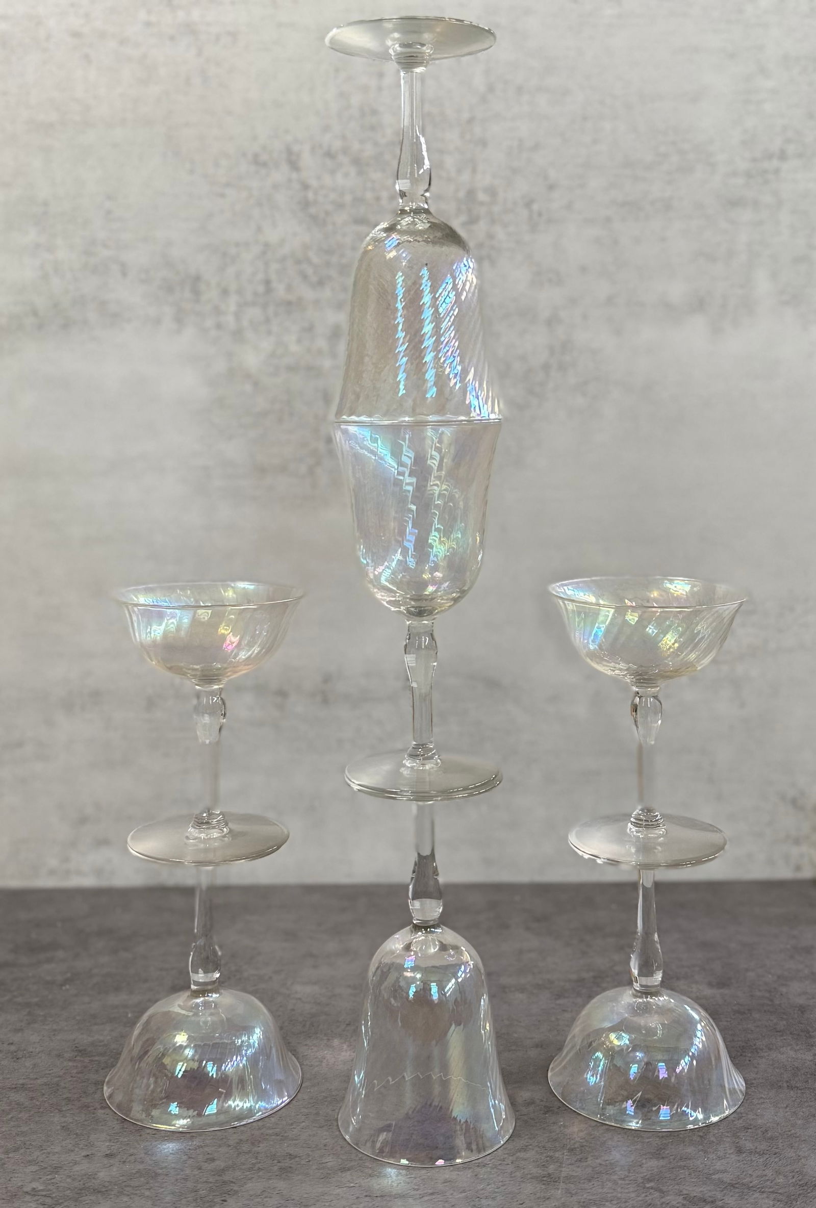 Set of Iridescent Glass Stemware, Vintage Style Cocktail Glasses: A decorative set of iridescent glass stemware featuring a soft rainbow sheen across the surfaces.The group includes multiple stemmed glasses with elegant proportions and flared forms, displaying a