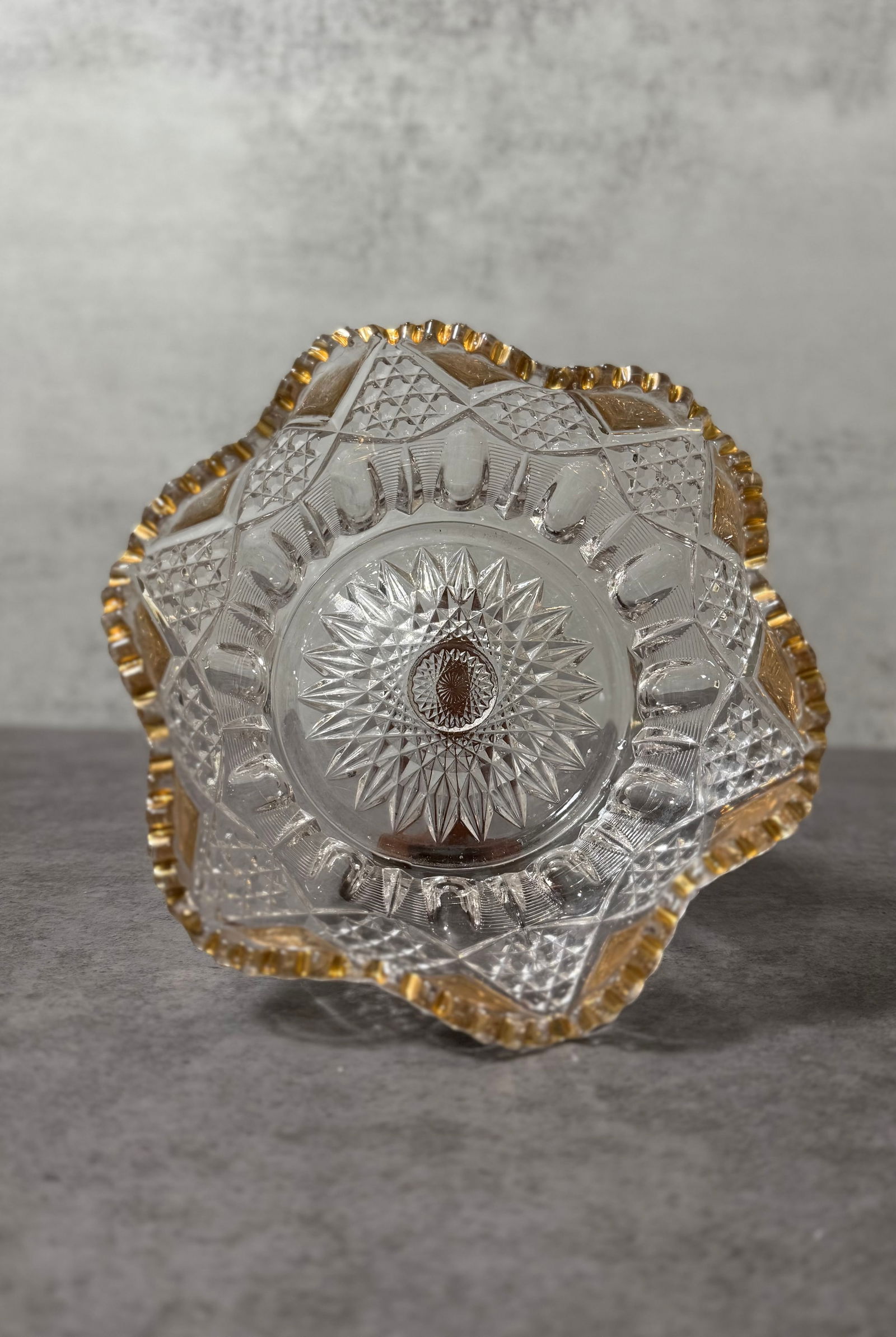 Vintage Pressed Glass Bowl with Gold Rim, Starburst Pattern: A vintage pressed glass bowl featuring a scalloped form with a gilt-accented rim.The bowl is richly molded with a central starburst motif surrounded by geometric patterns, creating a brilliant