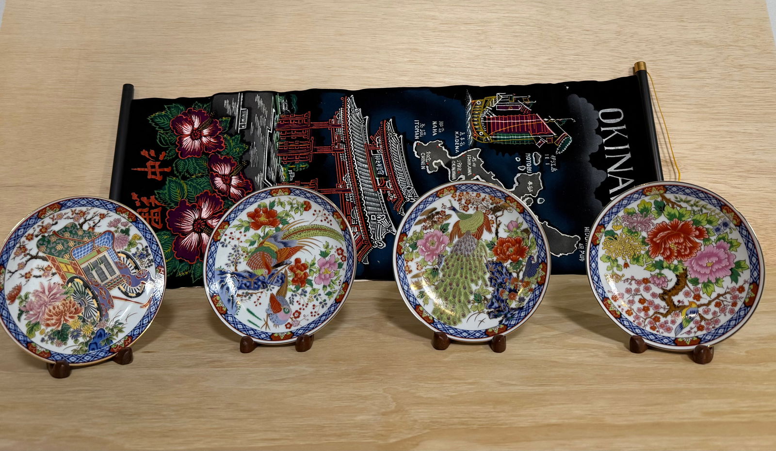 Japanese Imari Porcelain Plate Set 4 Peacock Floral + Okinawa Souvenir Scroll: A charming lot of Japanese souvenir collectibles, including four Imari-style porcelain decorative plates and one Okinawa souvenir scroll banner.The four plates feature vibrant designs including